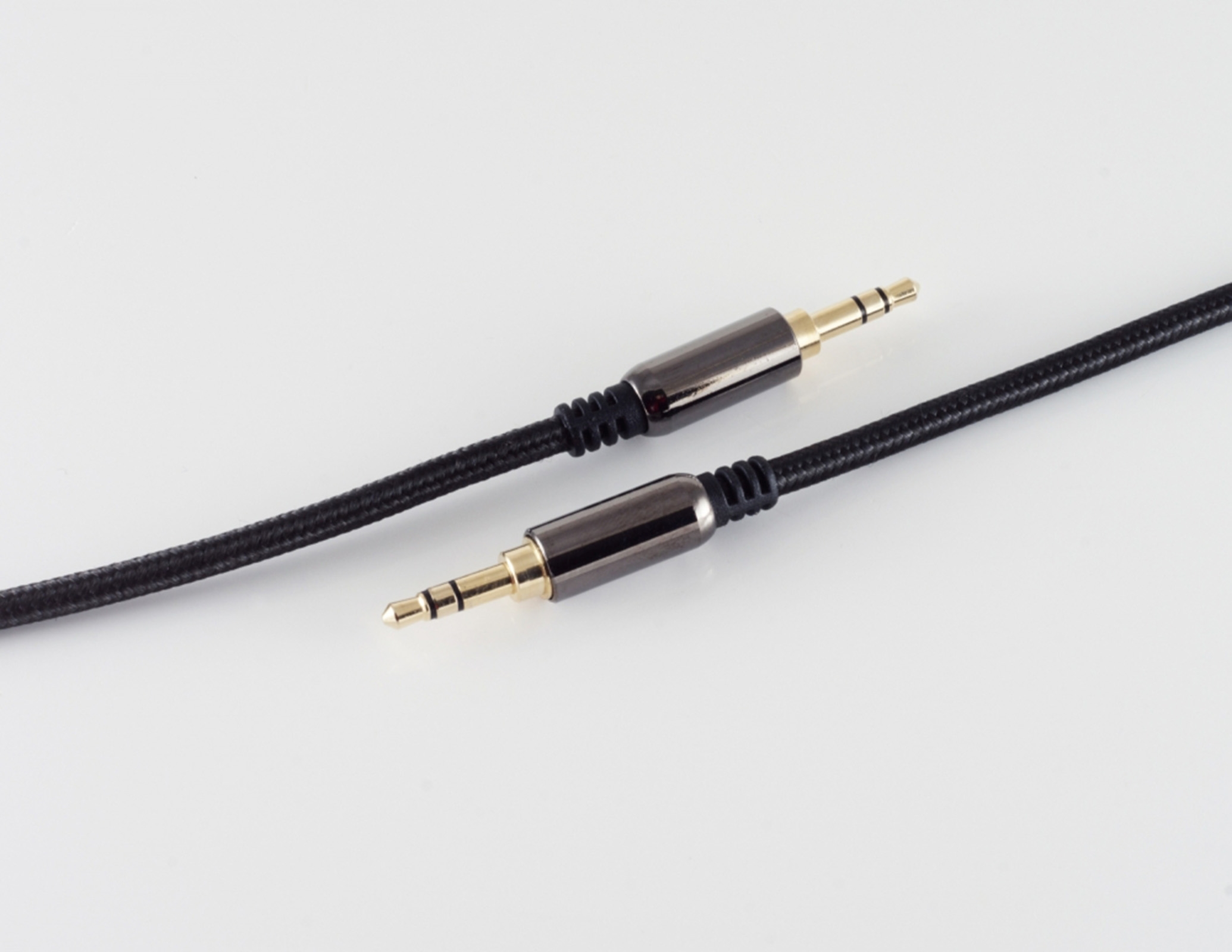 Zwei schwarze Audiokabel mit goldfarbenen Steckern, auf weißem Hintergrund.
