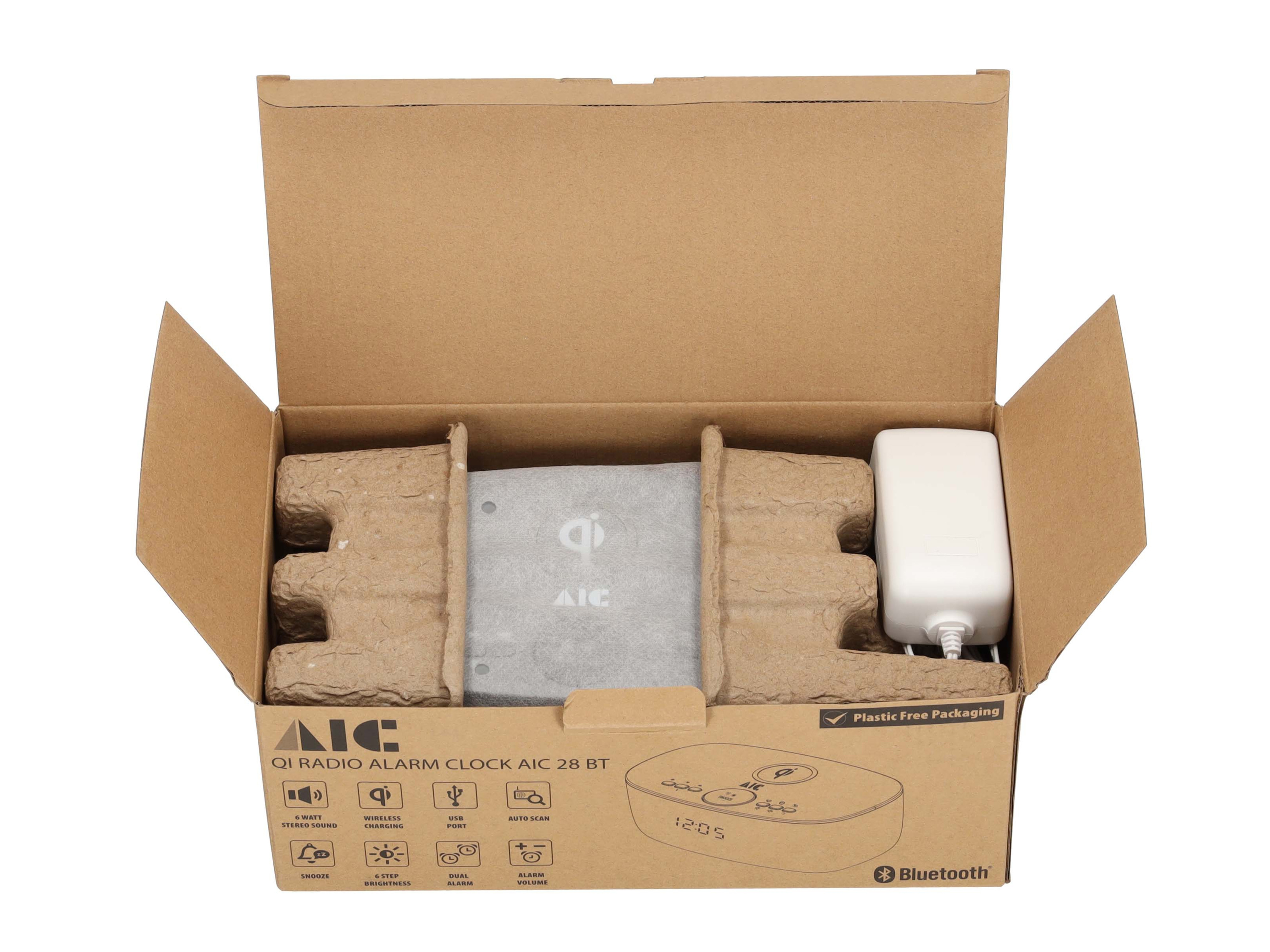 Weckradio in einem offenen Karton. Enthält ein Netzteil und Verpackungsmaterial.