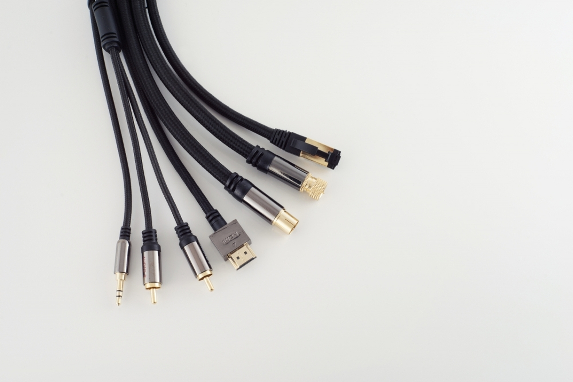 Verschiedene schwarze Kabel mit unterschiedlichen Steckern sind auf einer weißen Oberfläche ausgebreitet.