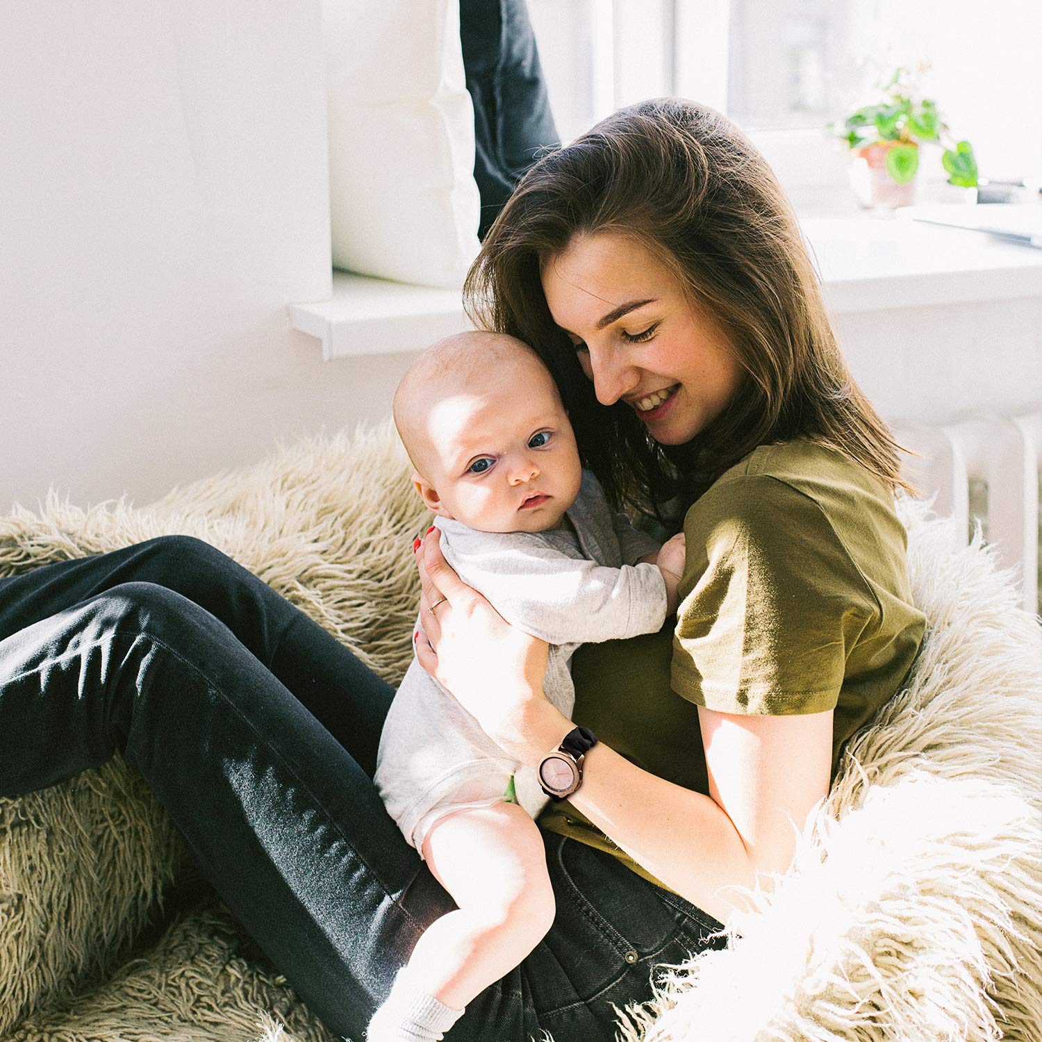 Eine Frau lächelt und hält ein Baby drinnen.