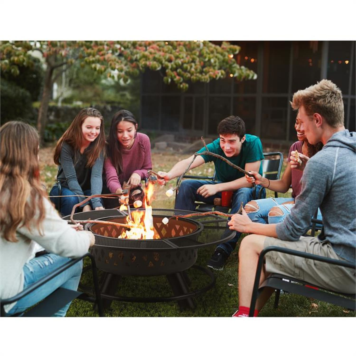 Gruppe von Leuten, die Marshmallows über einem Lagerfeuer rösten, im Garten.