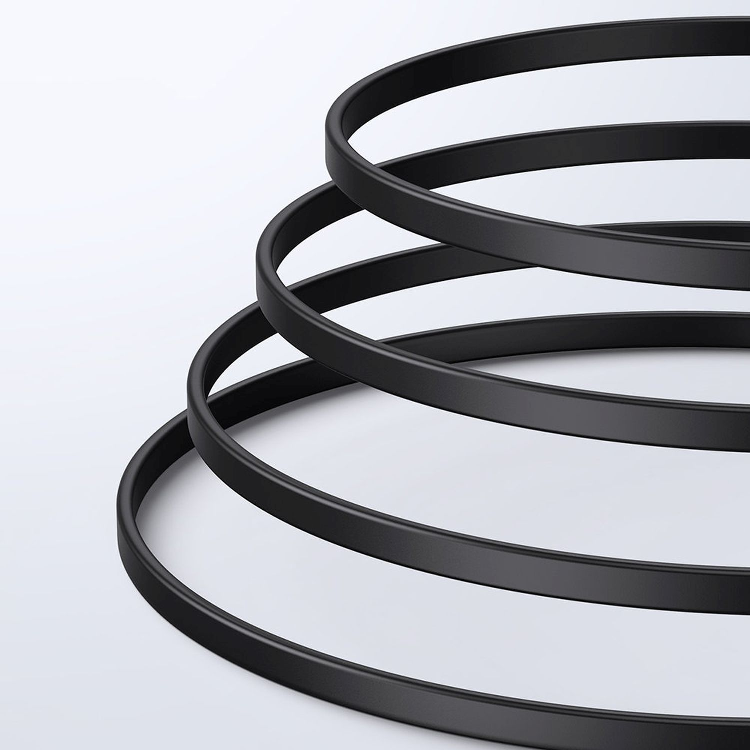 Vier schwarze Ringe, spiralförmig angeordnet. Sie befinden sich auf weißem Hintergrund. Die Ringe haben eine glatte Oberfläche.