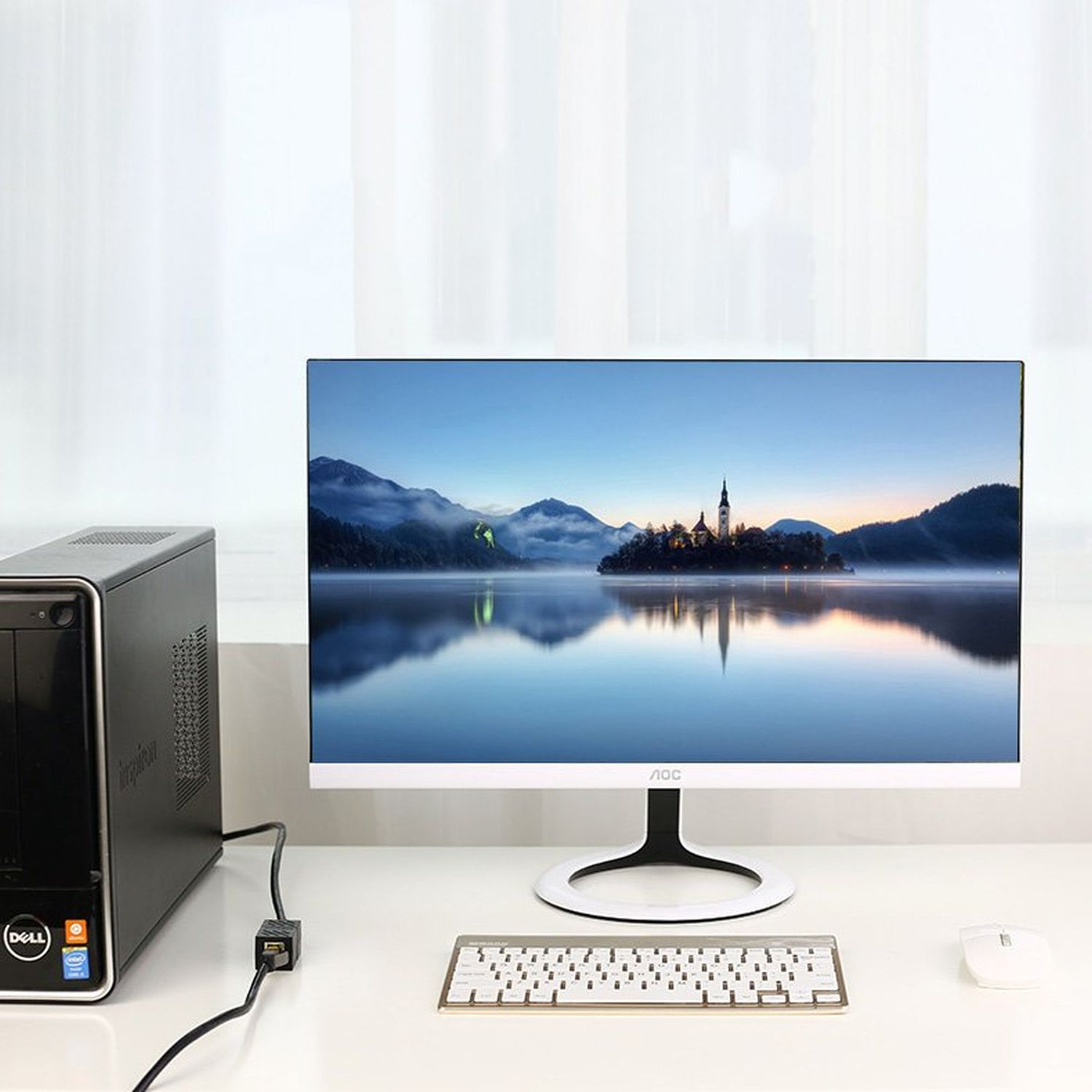 Computer-Setup auf einem weißen Schreibtisch: Monitor, Tastatur, Maus und schwarzer PC-Turm.