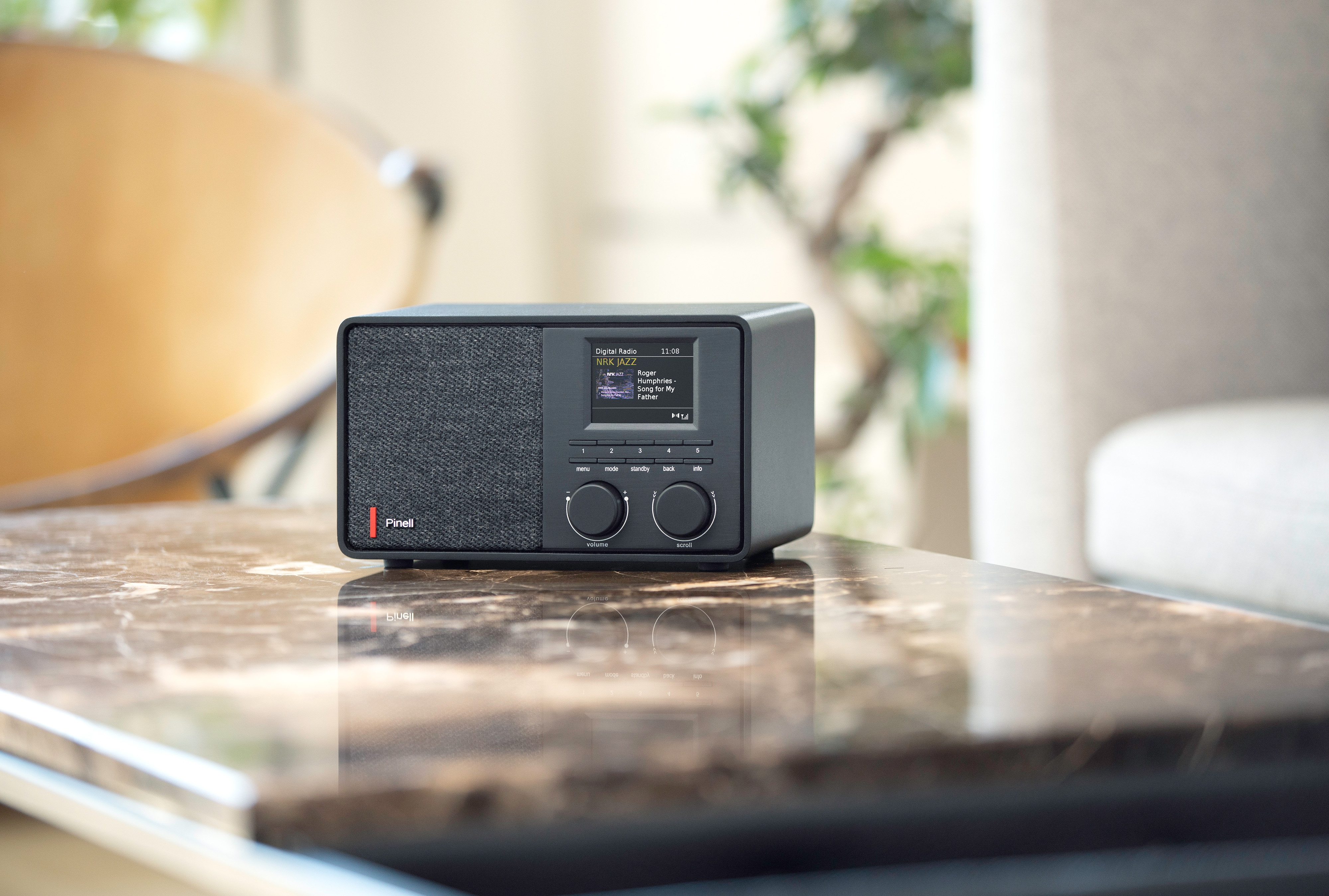 Radio digitale nera su un tavolo di marmo, con display e pulsanti.