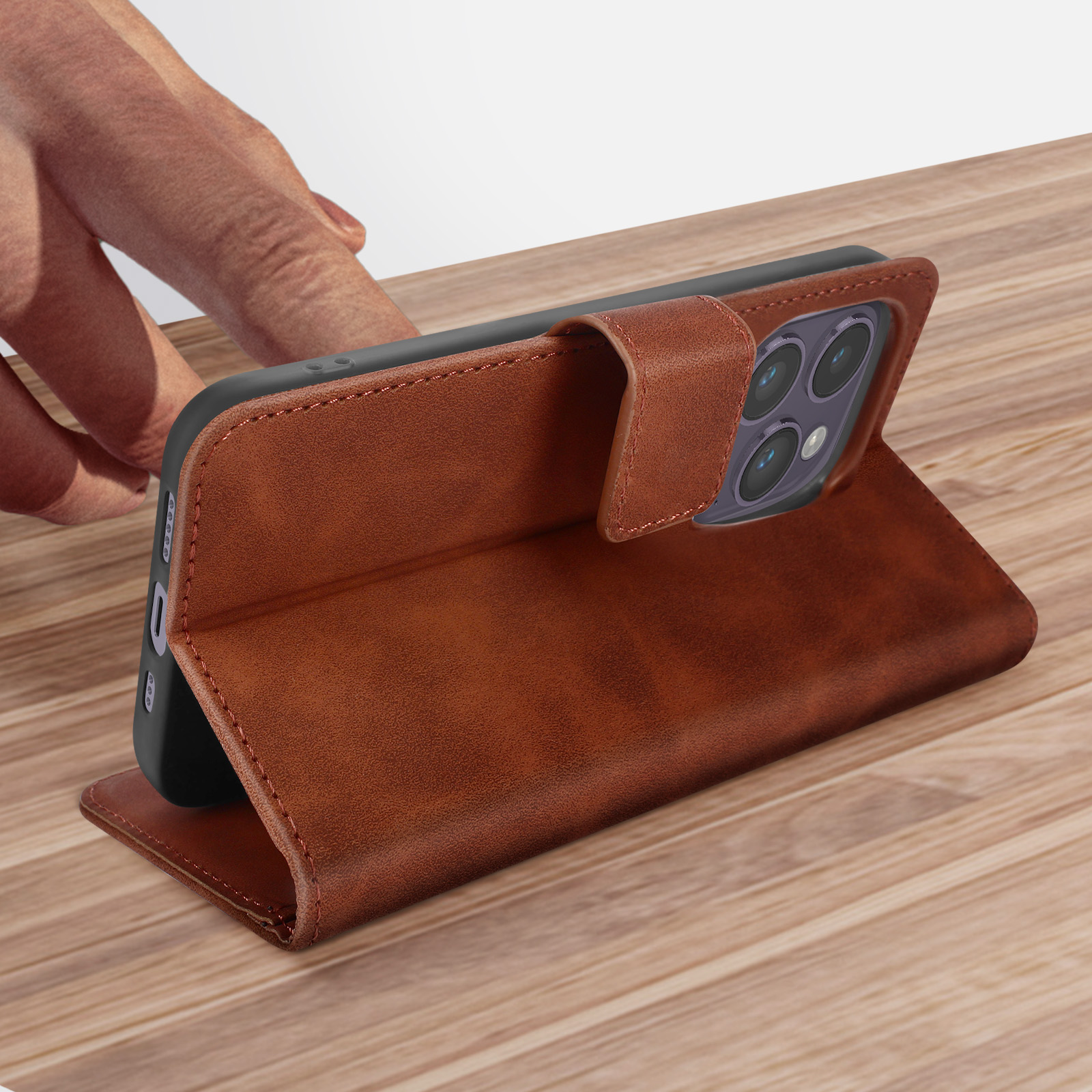 Custodia per telefono in pelle marrone su superficie di legno. Una mano tiene il telefono.