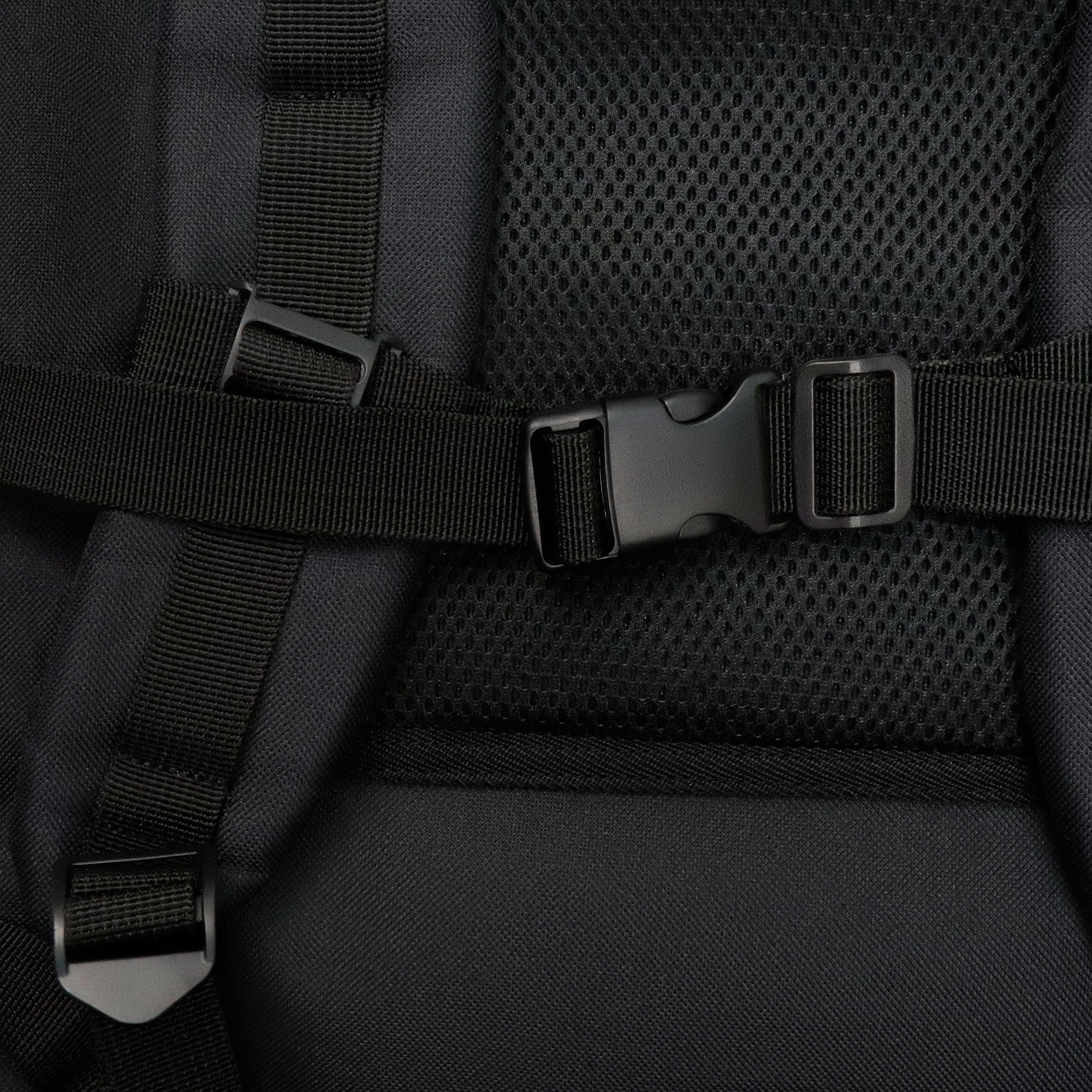 Detail eines schwarzen Rucksacks, der Träger, Schnalle und Netz-Rückwand zeigt.