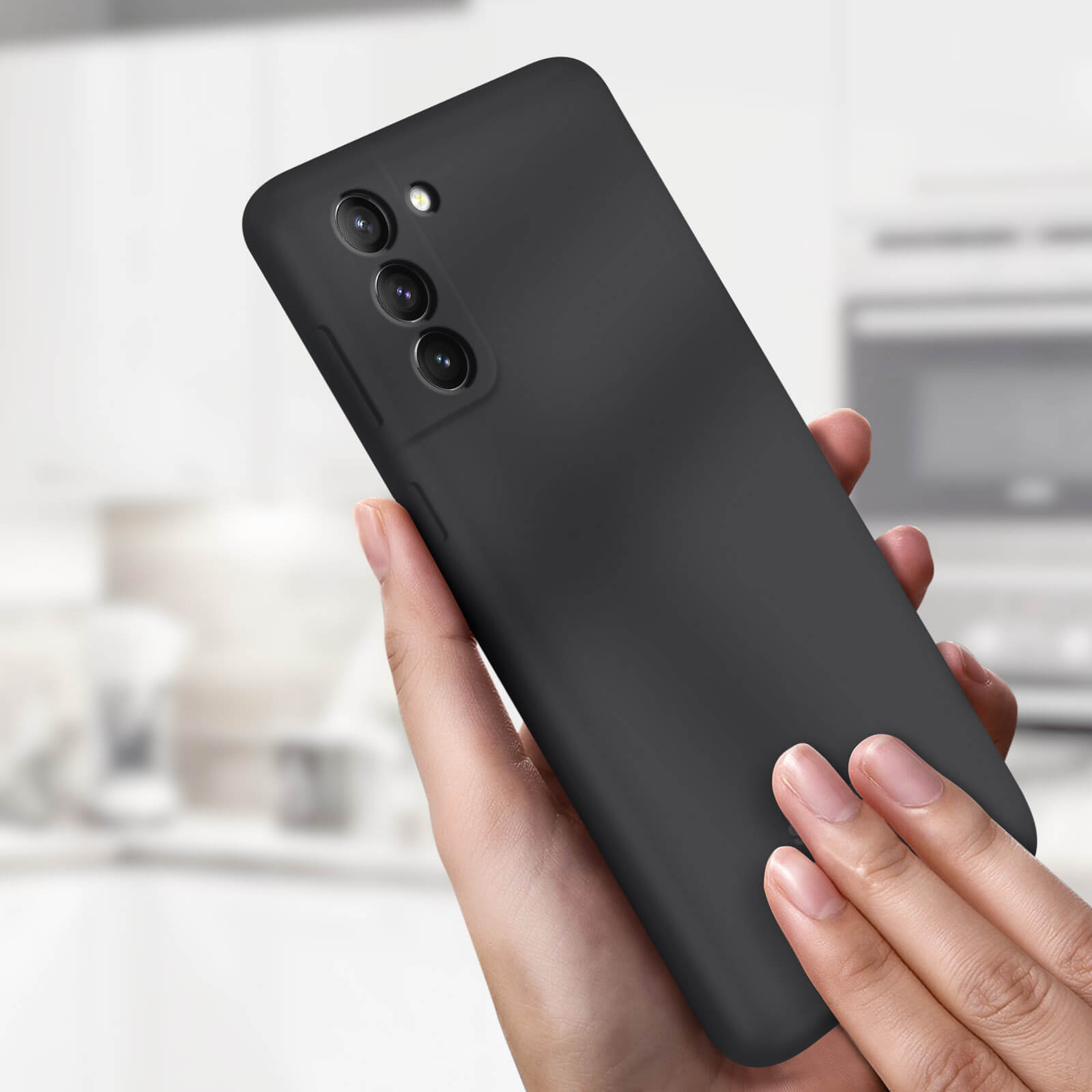 Ein schwarzes Smartphone, das von einer Hand gehalten wird und die Rückkamera zeigt. Ein verschwommener Hintergrund ist sichtbar.