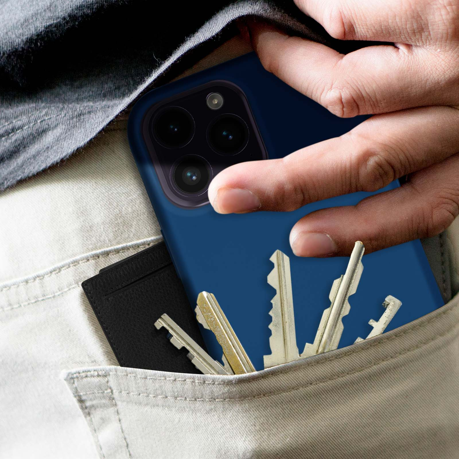 Main dans la poche avec clés et téléphone dans une coque bleue. La poche est dans un pantalon.