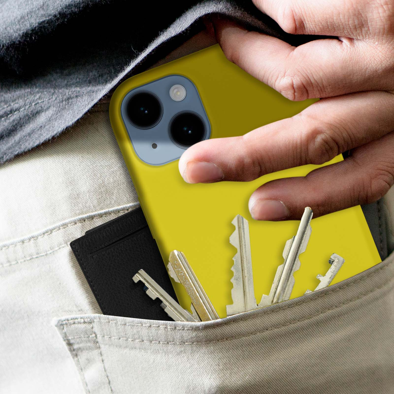 Hand in zak met gele telefoonhoes, sleutels en kaarthouder. De telefoon is felgeel.