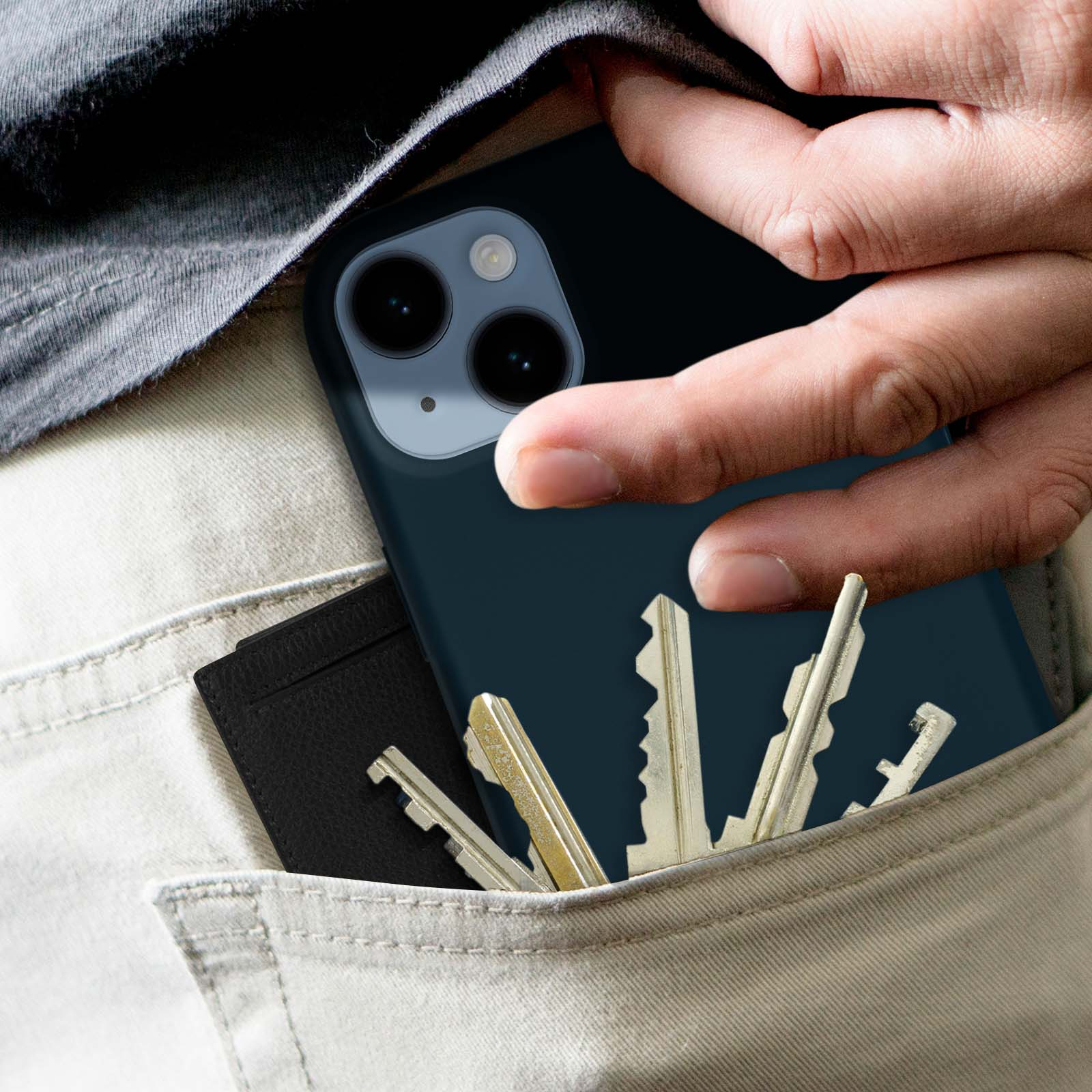 La tasca di una persona con un telefono e delle chiavi, contro uno sfondo chiaro.