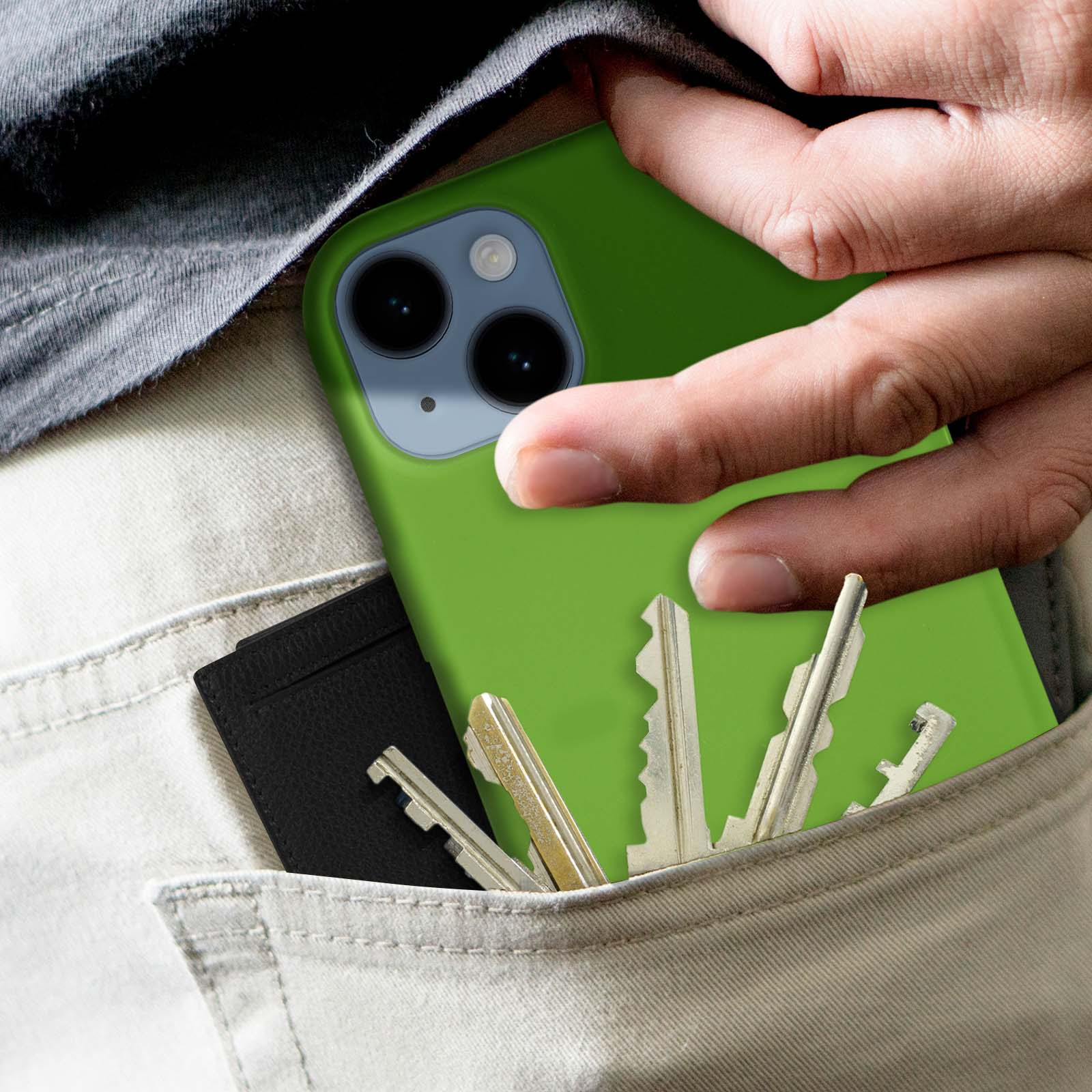 Una mano che tiene un telefono verde in tasca con chiavi e un porta carte.