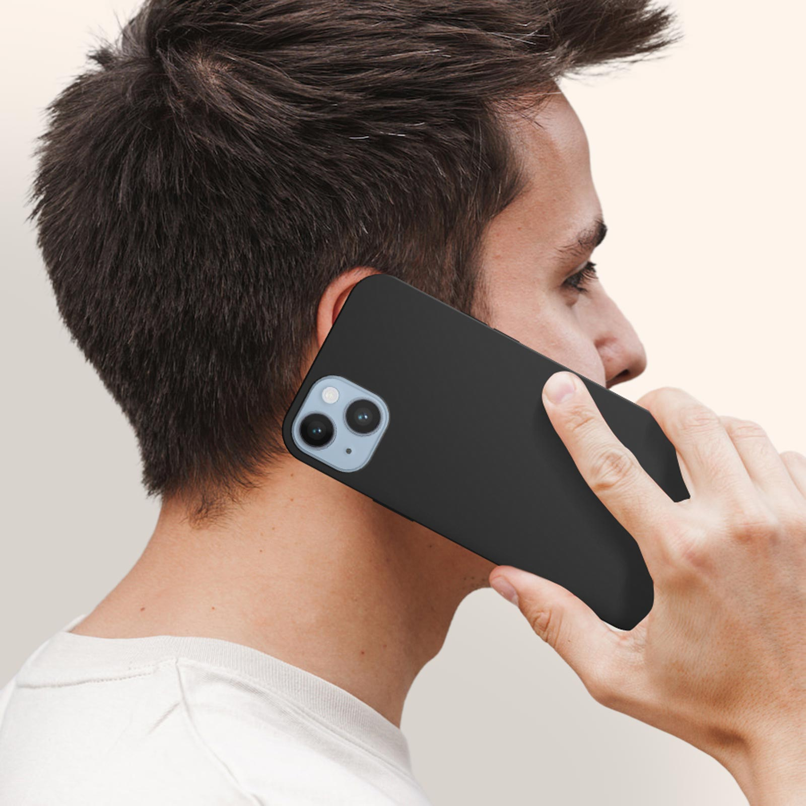 Een man houdt een zwarte telefoon tegen zijn oor. Hij draagt een wit t-shirt.