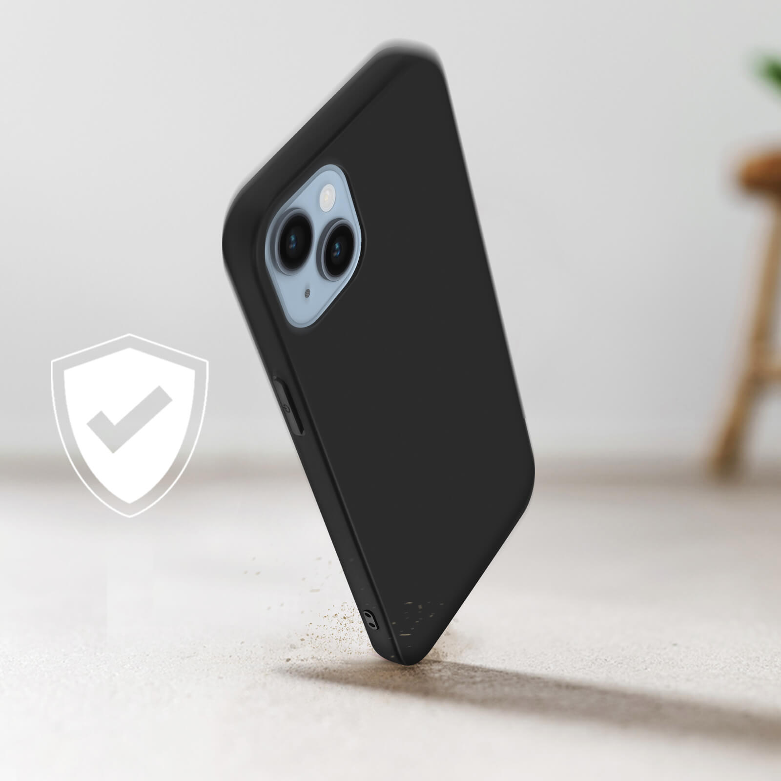 Un étui de téléphone noir tombe. Un logo de bouclier de protection est à gauche. L'étui est sur une surface claire.
