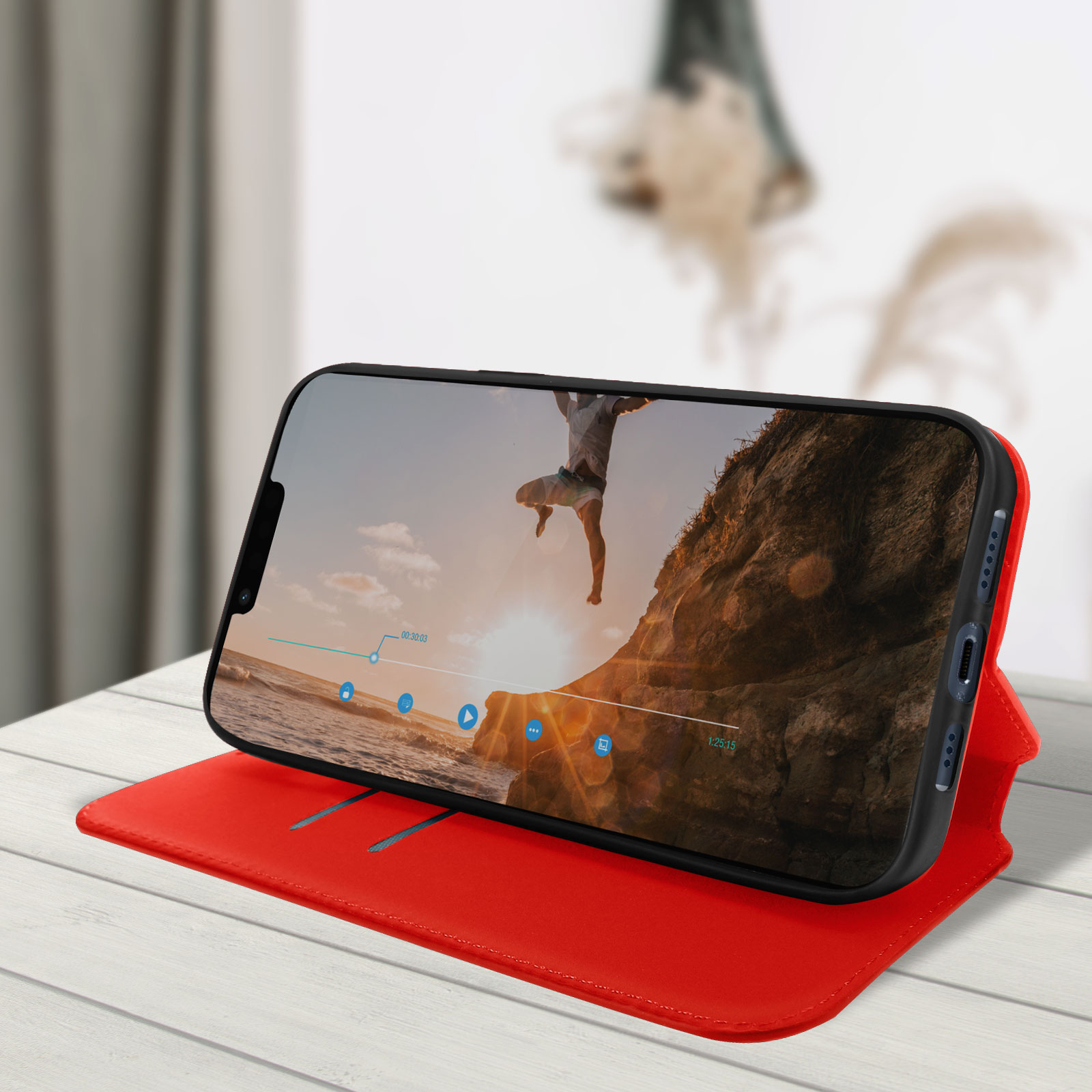 Telefoon met een video van een springende man. Rode hoes op een houten tafel.