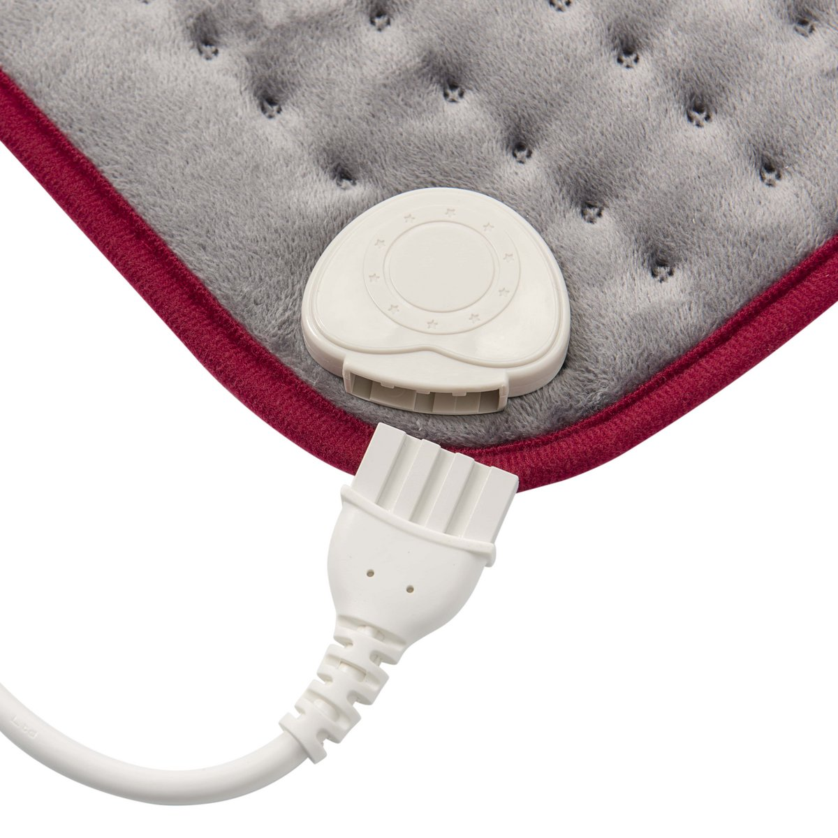 Una almohadilla térmica gris con conector de alimentación blanco y borde rojo, primer plano.