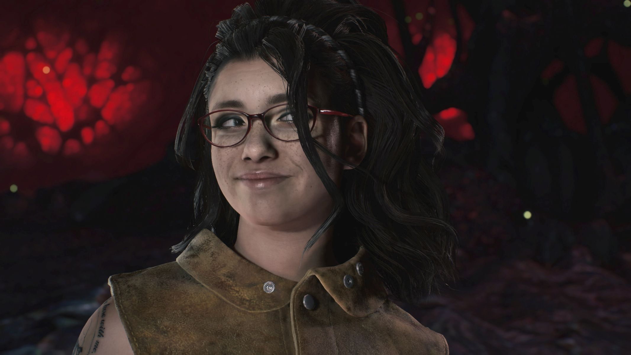 Kobieta w okularach uśmiechająca się. Ciemne włosy, brązowa skórzana kurtka i czerwone tło.