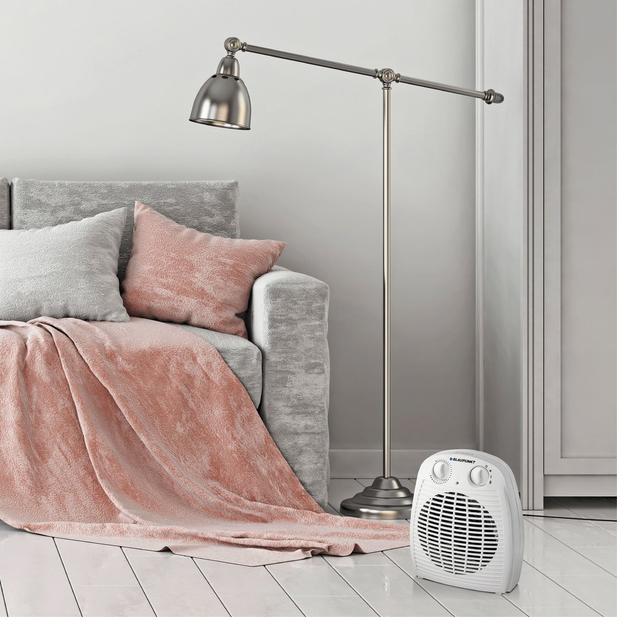 Lampada da terra e termoventilatore vicino a un divano con coperta e cuscini in un ambiente.