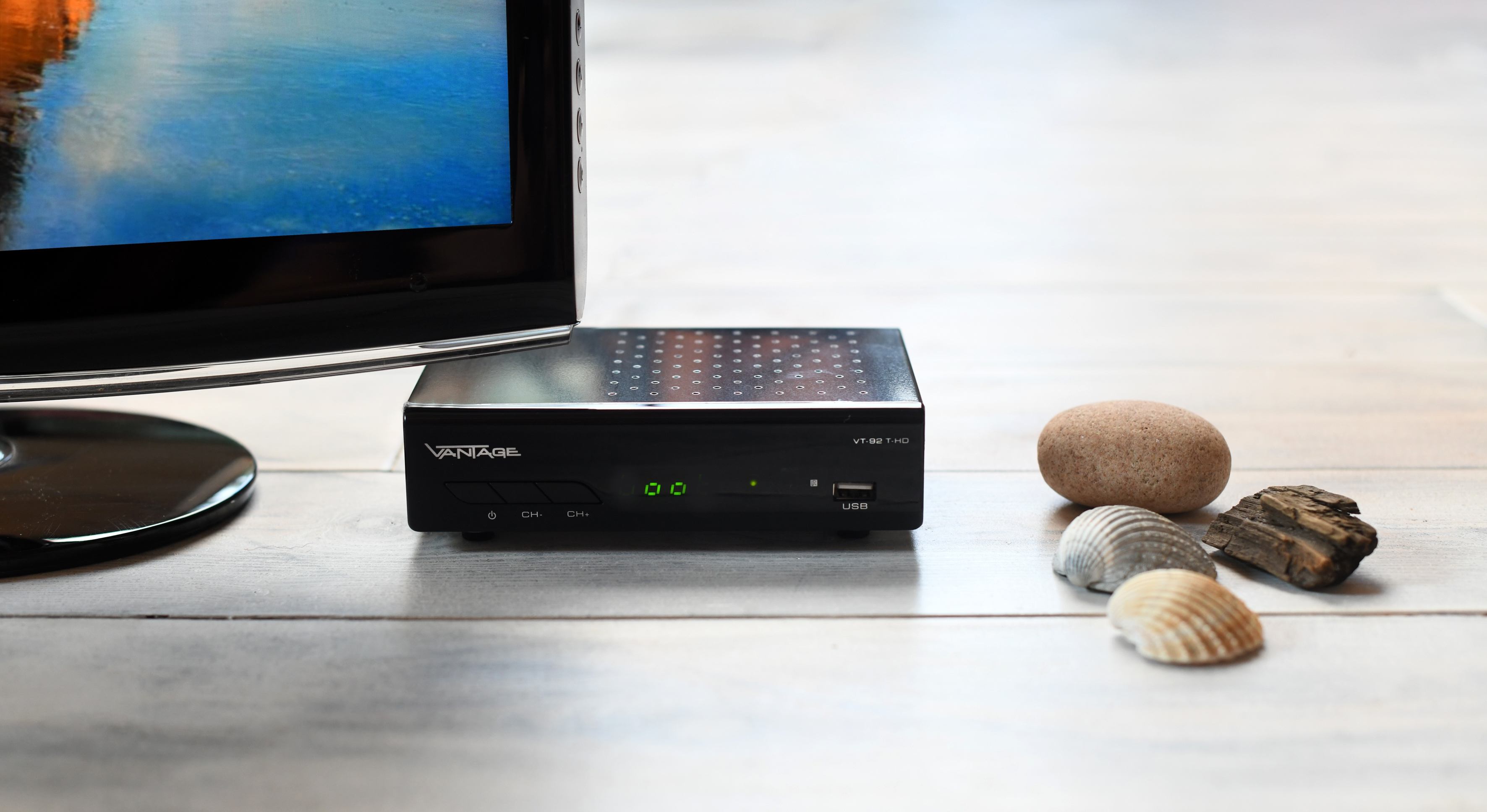 Schwarze Set-Top-Box mit Bildschirm und Muscheln. Die Box zeigt eine Zeit an.