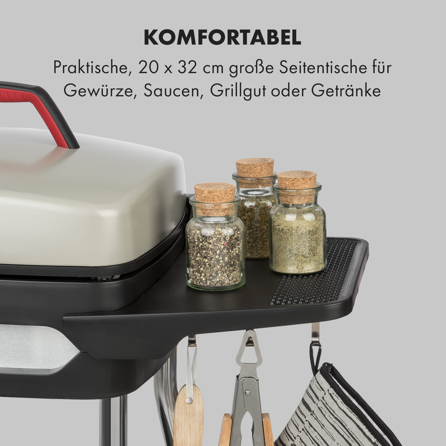 Ein schwarzes Regal mit Gewürzgläsern, Zangen und Utensilien, die darunter hängen, mit Text auf Deutsch.