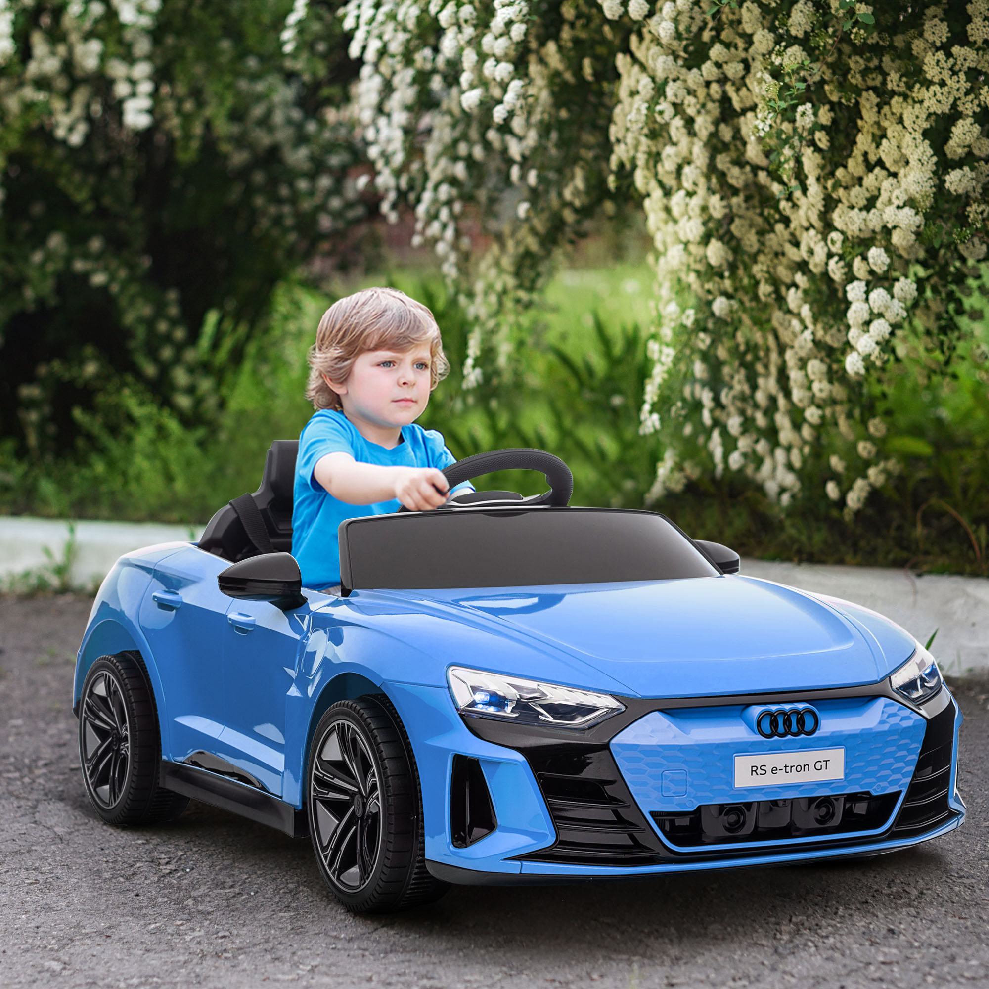 Niño en camisa azul conduce un coche de juguete azul al aire libre. Fondo verde.