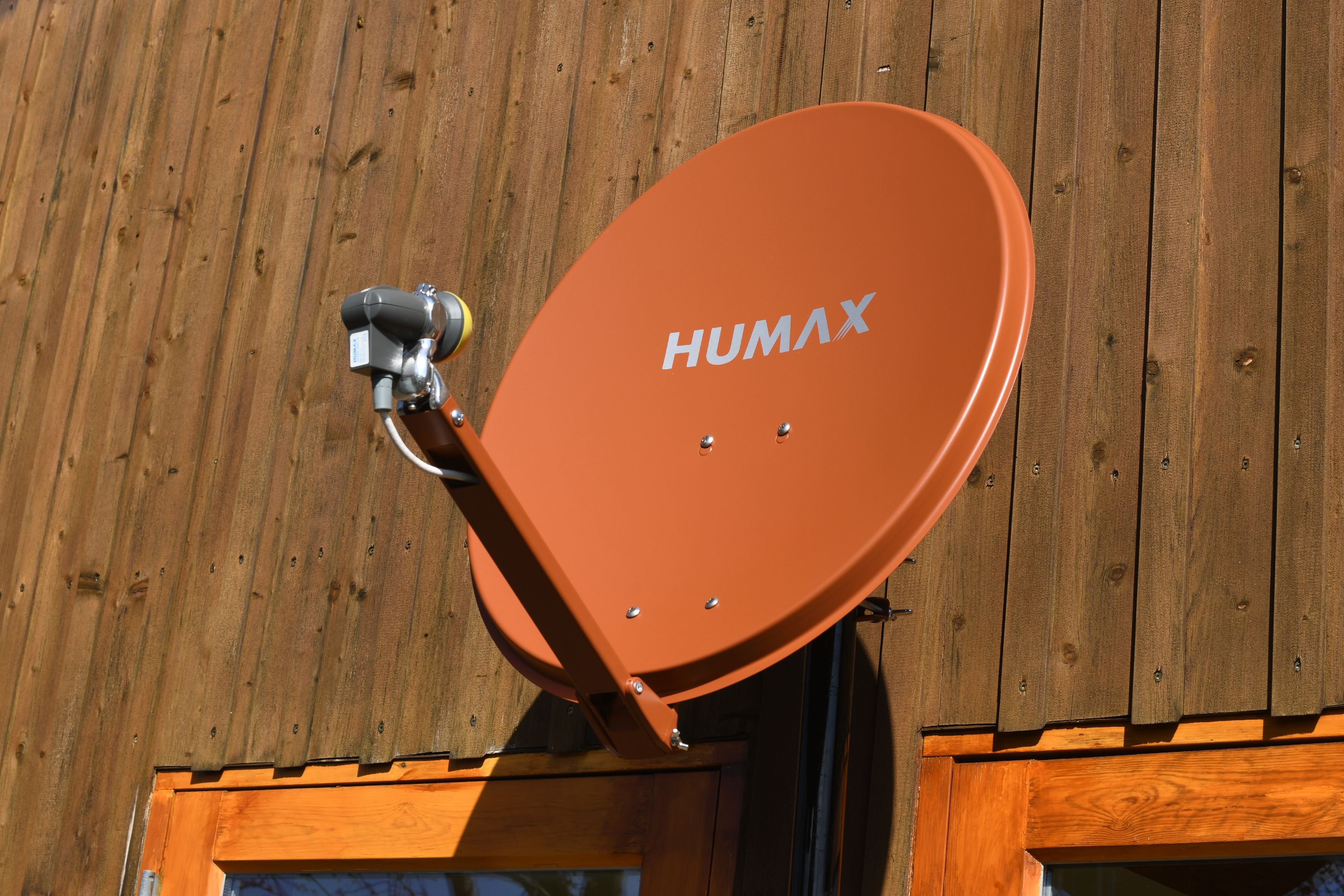 Eine braune Humax-Satellitenschüssel an einer Holzwand. Die Schüssel ist angewinkelt.