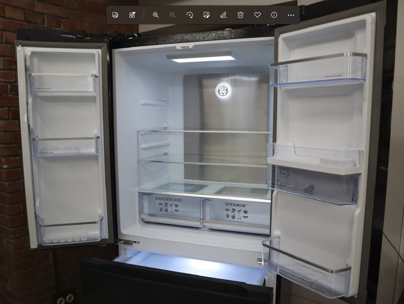 Ein offener Kühlschrank mit Regalen und Schubladen. Der Kühlschrank ist leer.