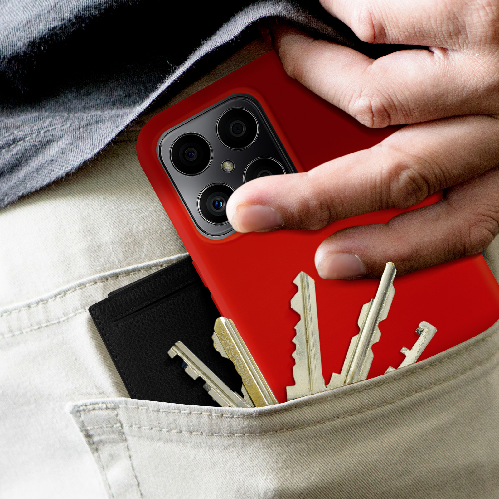 Mano che tiene telefono rosso con chiavi e carta in tasca.