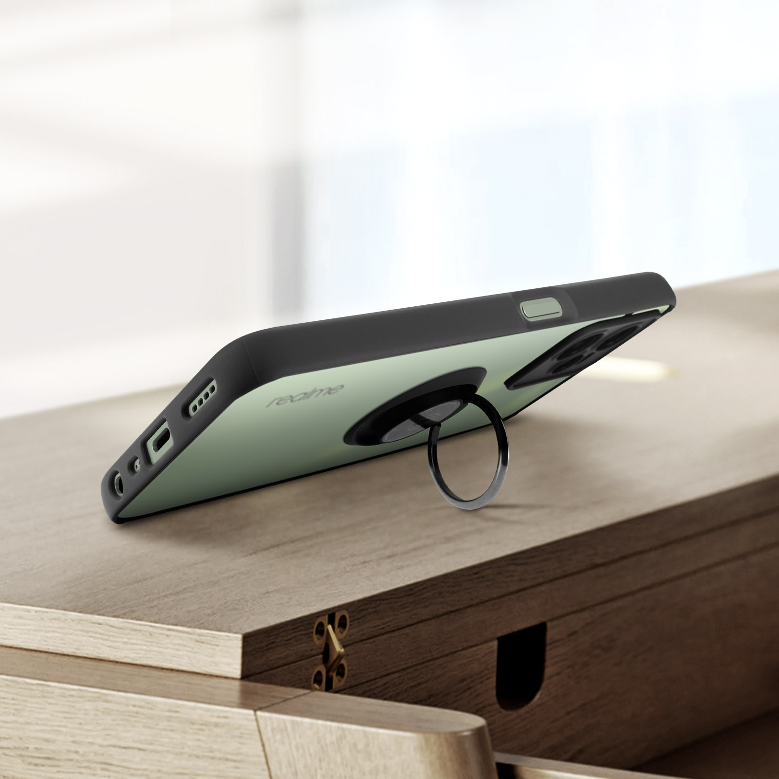 Un telefono con un anello di supporto, su una superficie di legno. Il telefono è verde chiaro, l'anello nero.