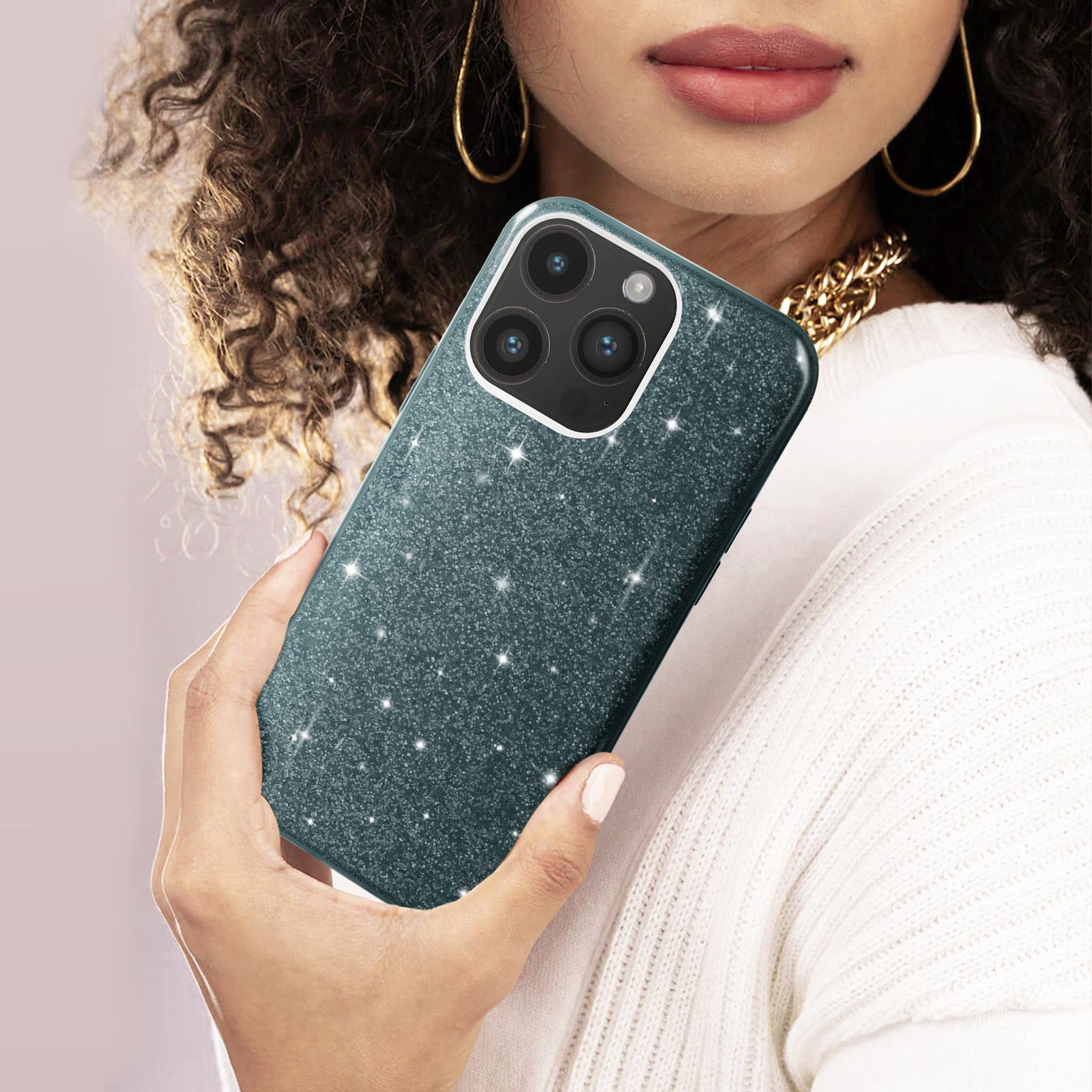Donna che tiene in mano una custodia per telefono glitterata verde acqua. Visibili orecchini e collana d'oro.