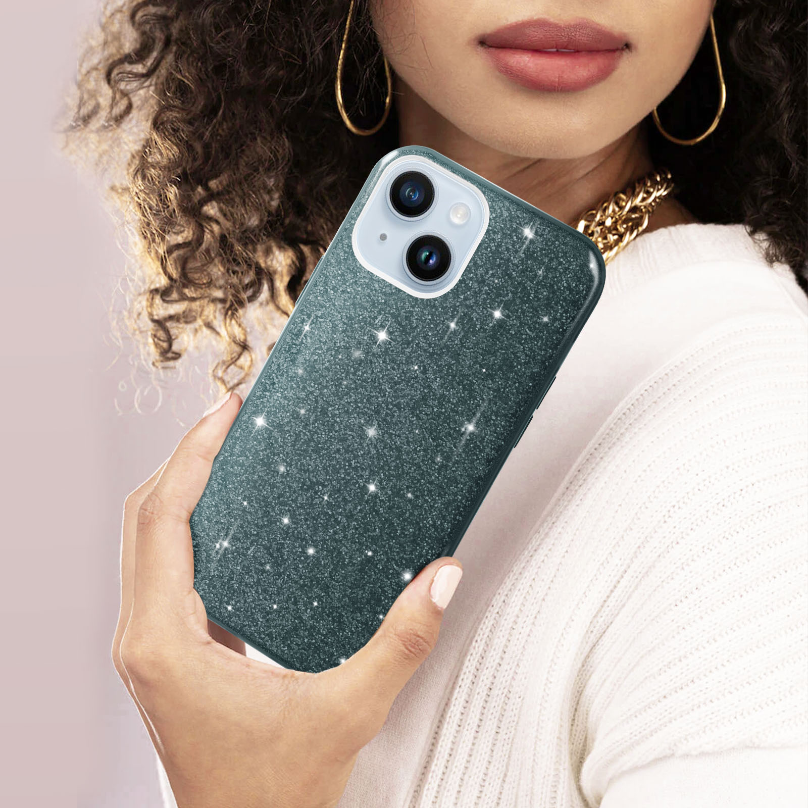 Persona che tiene una custodia per telefono glitterata con fotocamera. Sfondo maglione bianco.