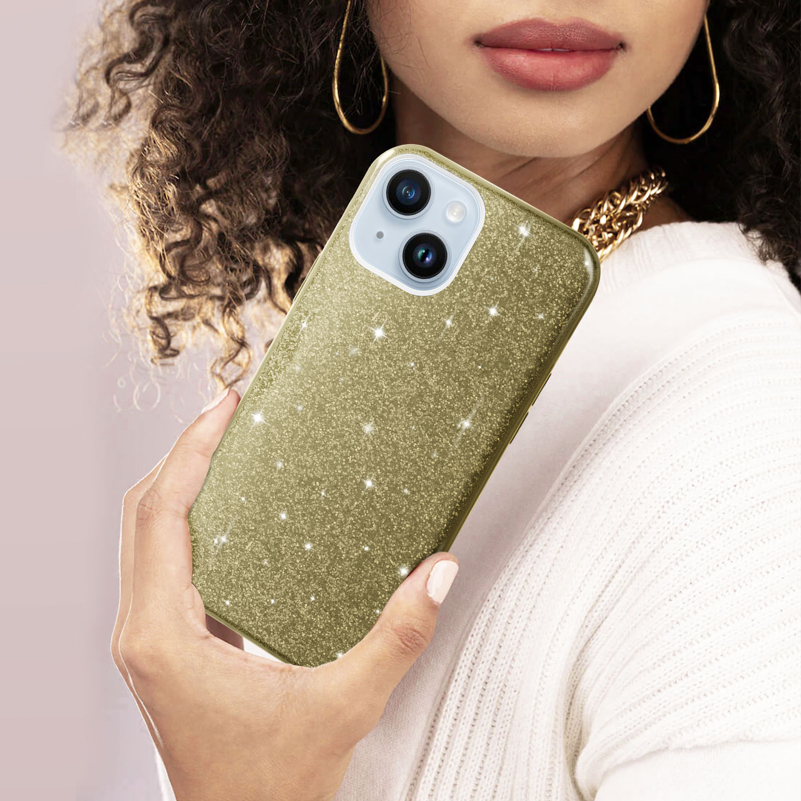 Une femme tenant une coque de téléphone dorée à paillettes, avec un collier doré.