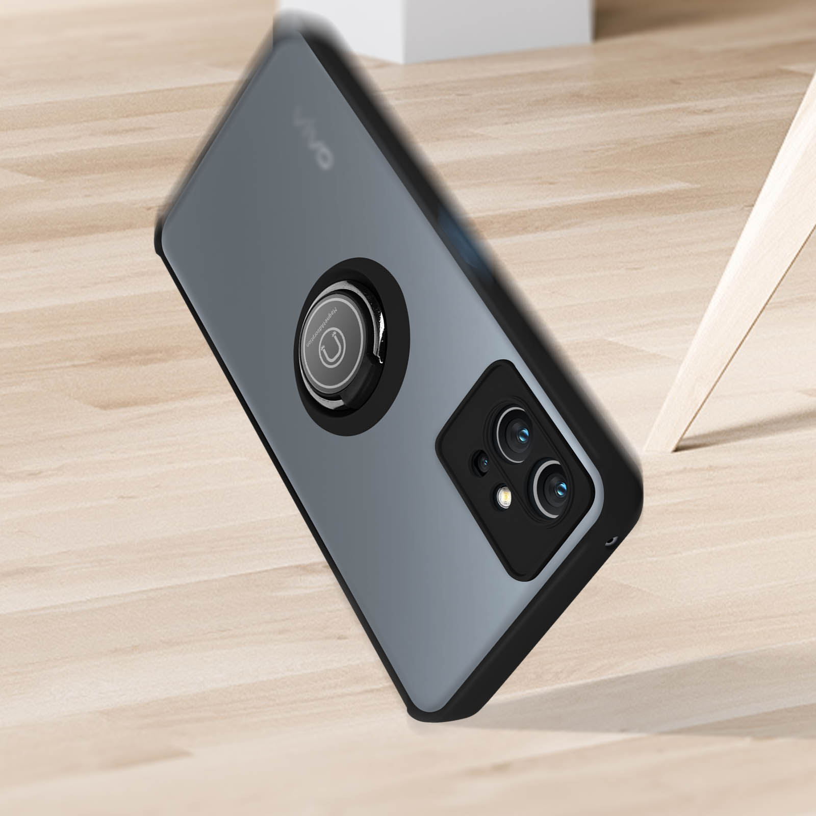 Una custodia per telefono con un supporto ad anello su una superficie in legno. La custodia è grigia e nera.