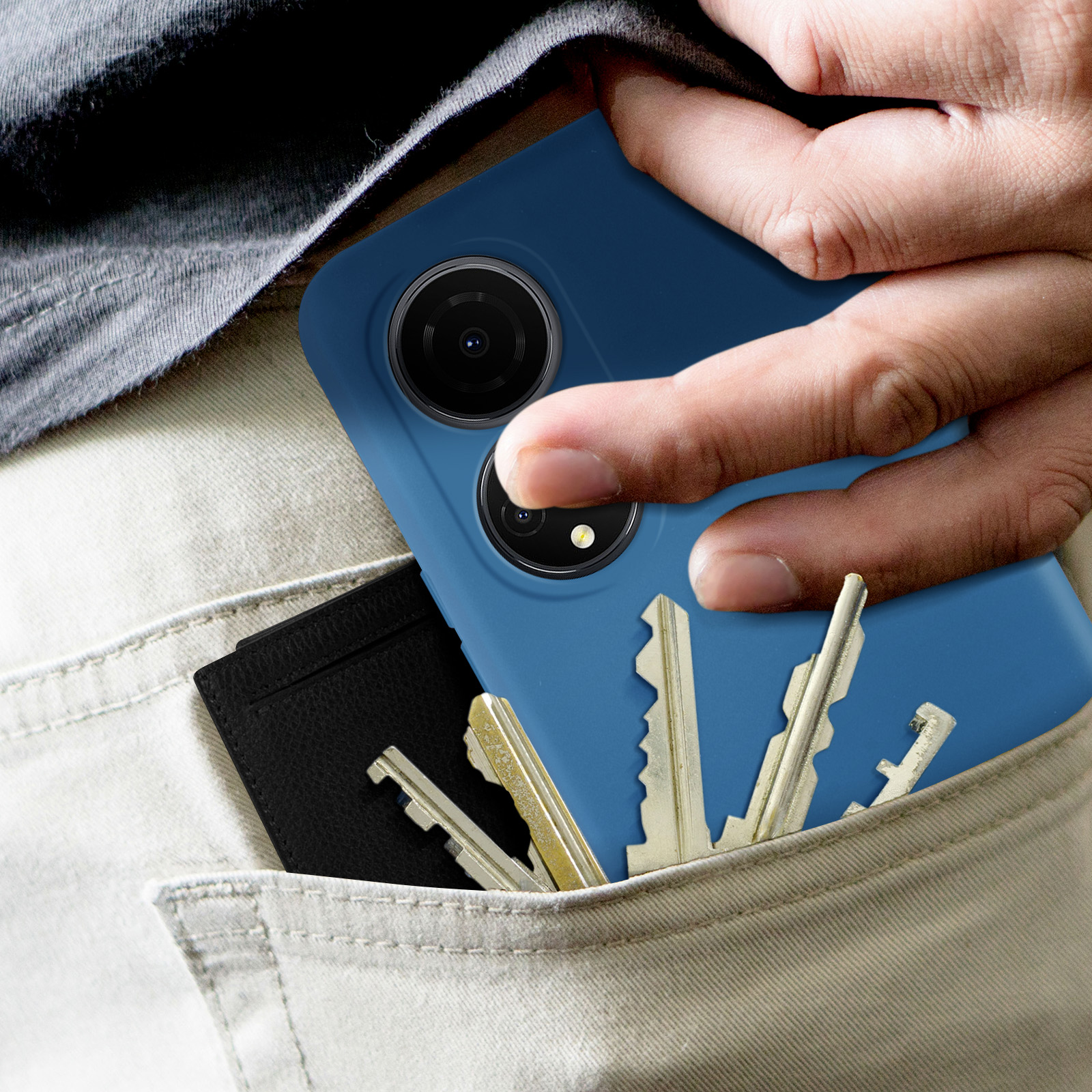 La mano di una persona in tasca che tiene un telefono blu e delle chiavi. Anche un portafoglio nero è in tasca.