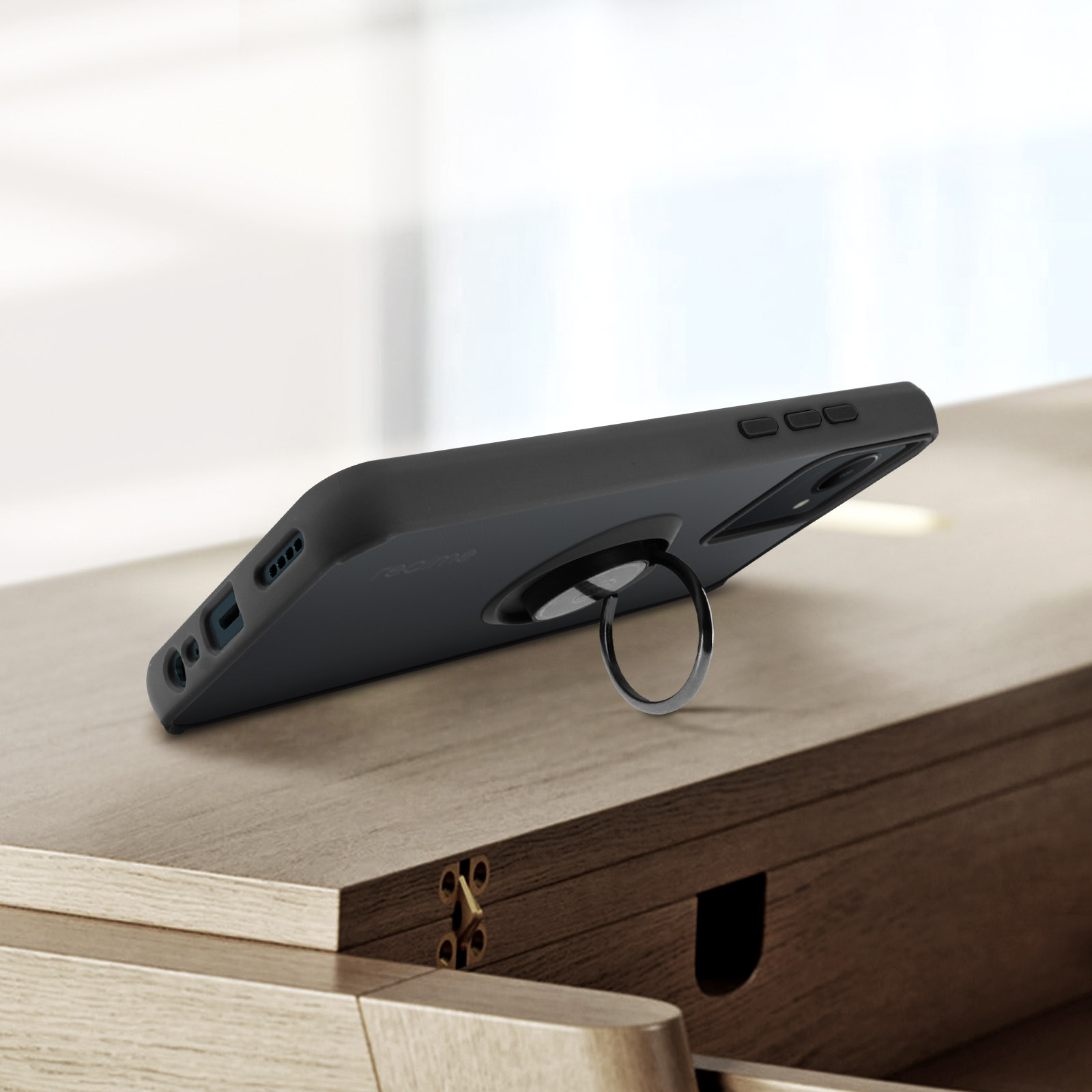 Custodia nera per telefono con un anello di supporto su una superficie di legno.