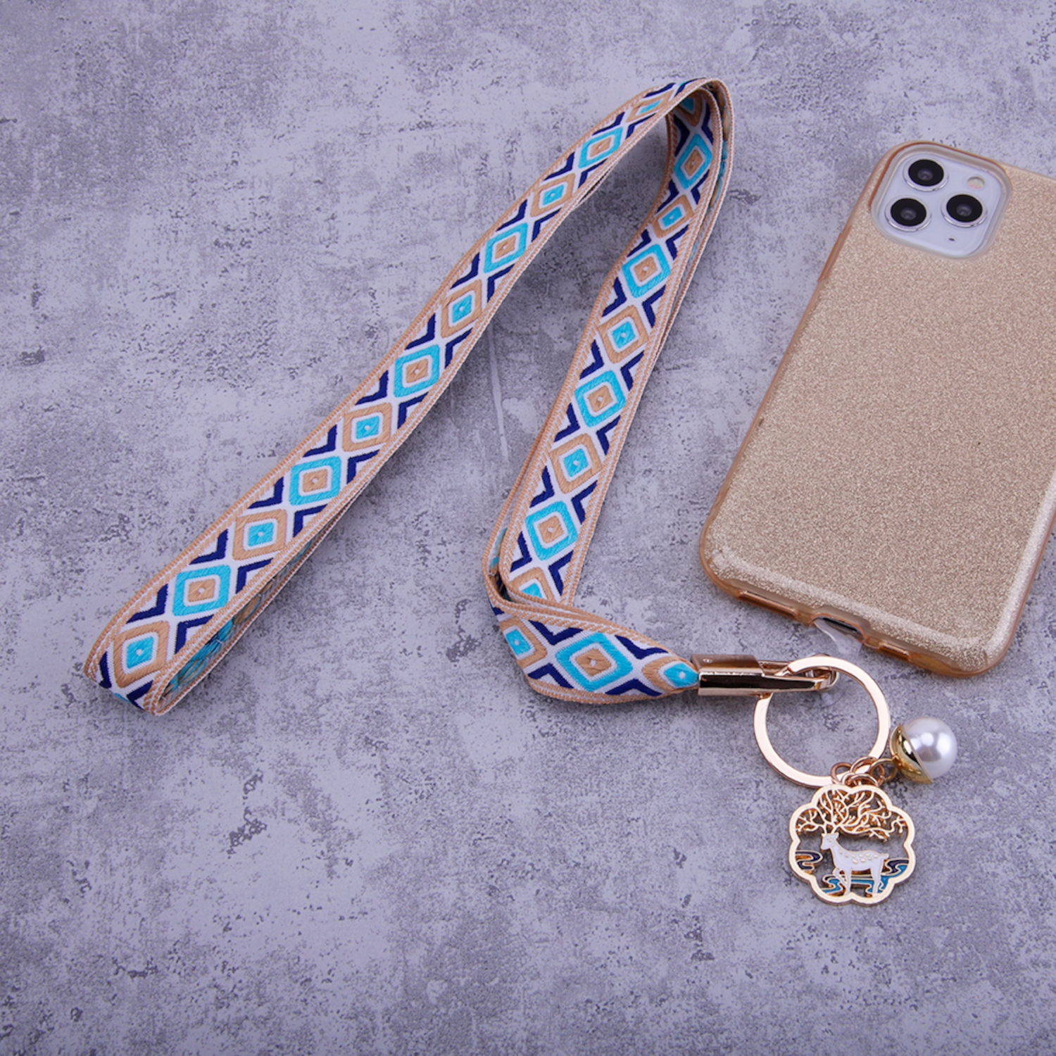 Ein Telefon mit Schlüsselband, goldene Handyhülle mit Anhänger.