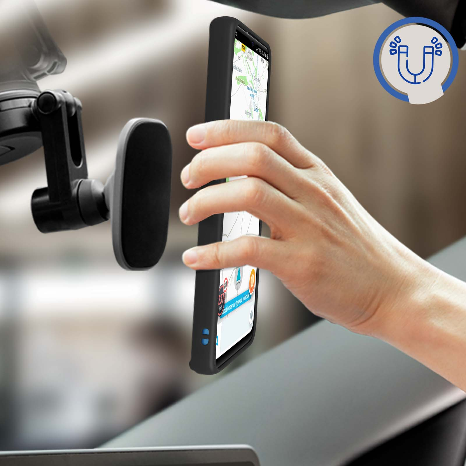Una mano che tiene un telefono nero con custodia, posto su un supporto per auto. L'interno dell'auto è sullo sfondo.