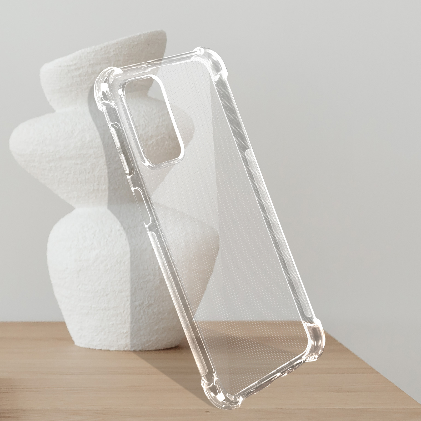 Una custodia trasparente per telefono appoggiata a un vaso bianco su un tavolo di legno.