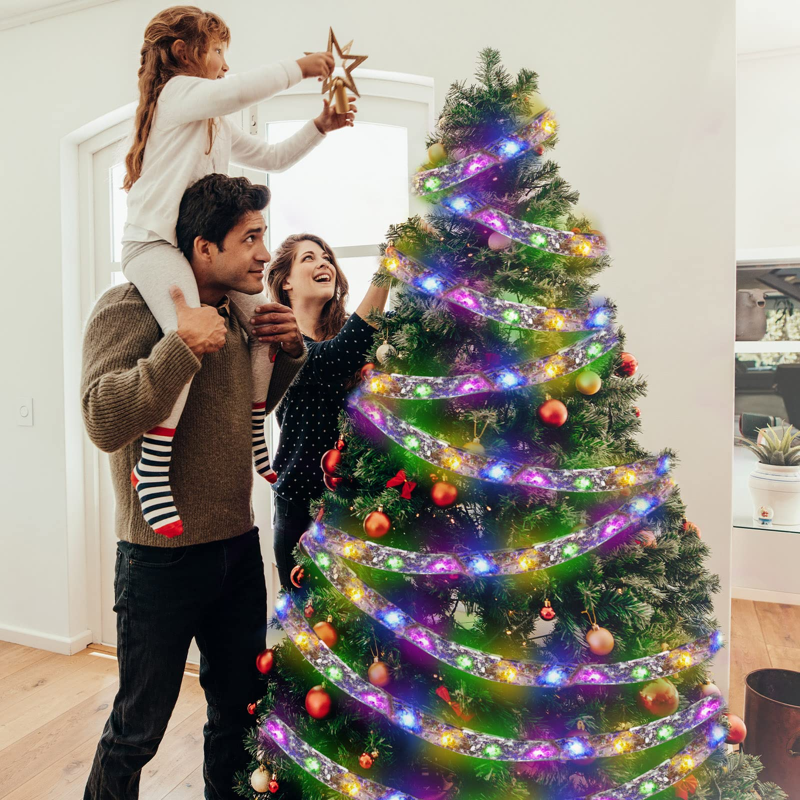 Familie schmückt einen Weihnachtsbaum mit Lichtern, Ornamenten und einem Stern oben drauf.