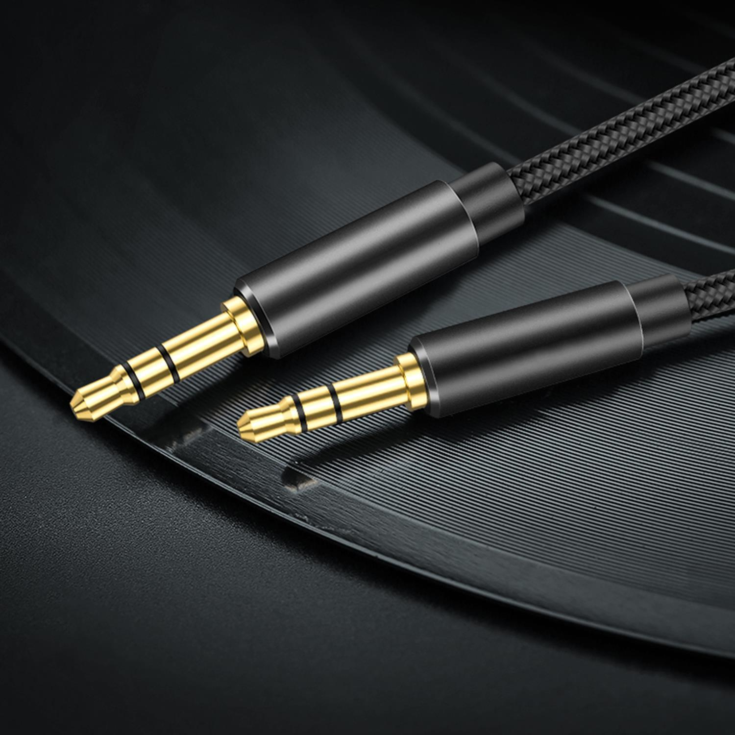 Primer plano de dos cables de audio de 3,5 mm negros y dorados, sobre una superficie oscura texturizada.