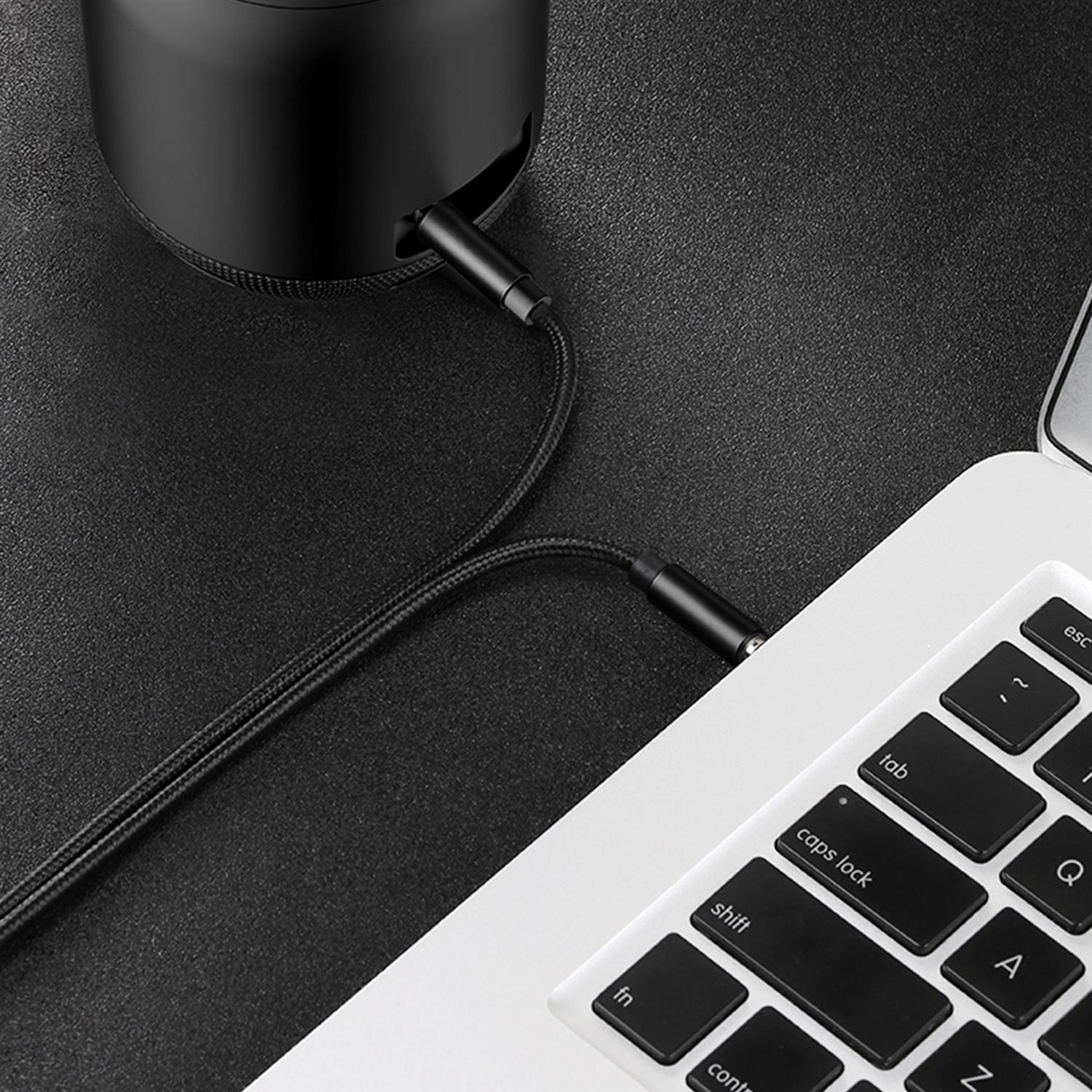 Cable USB-C negro conectado a altavoz negro y portátil blanco con teclas negras.