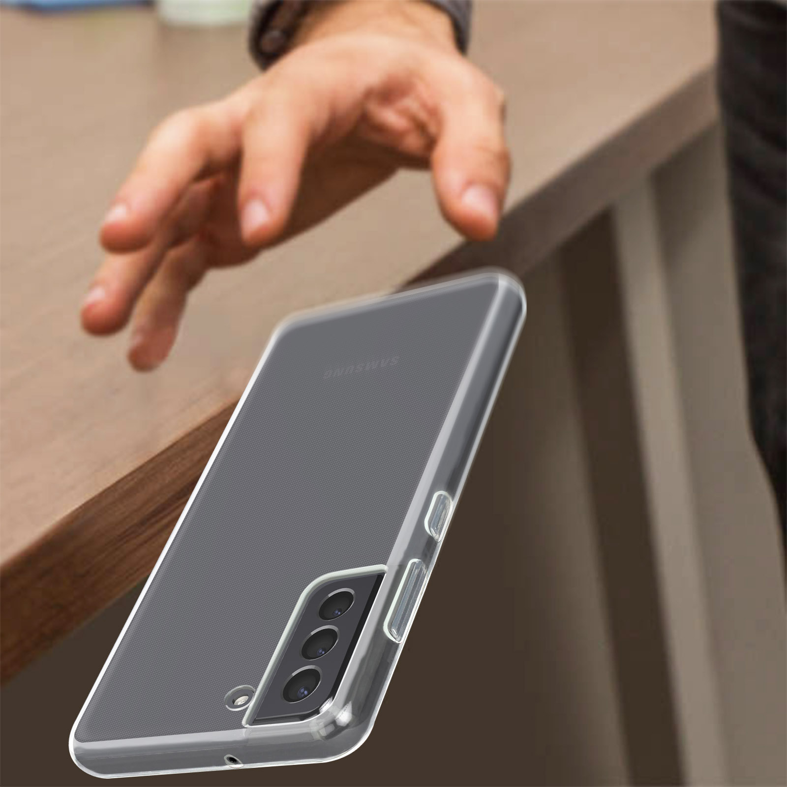 Una mano che raggiunge una custodia trasparente per telefono che si trova su un tavolo, con un telefono all'interno.