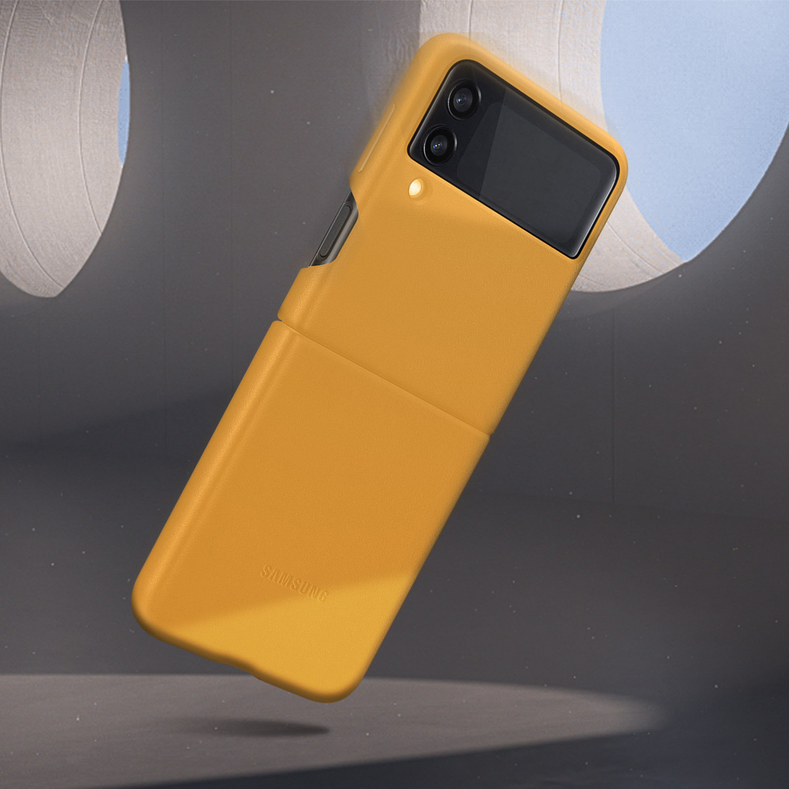 Funda de teléfono amarilla, abierta, sobre un fondo de cielo azul y estructuras blancas.