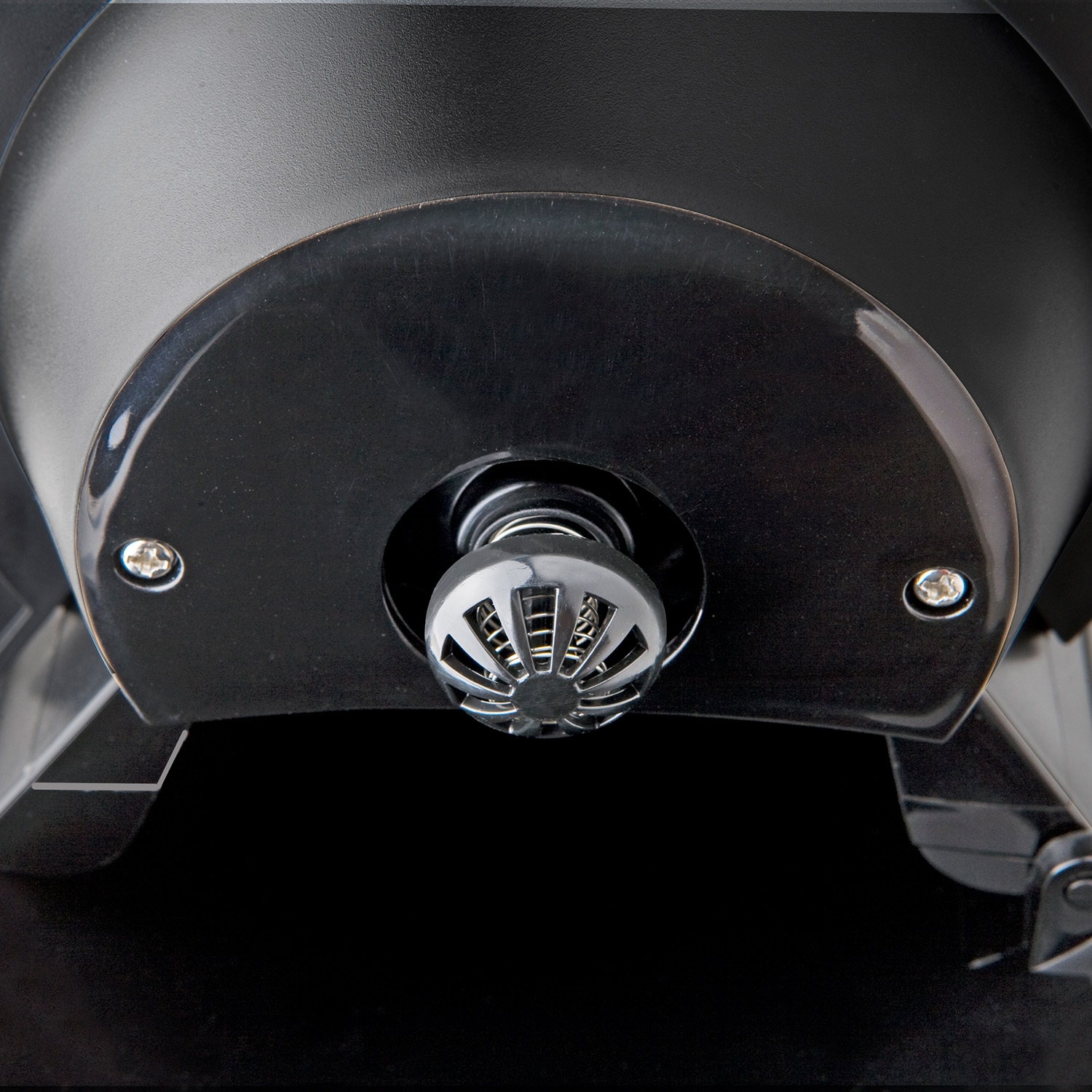 Zbliżenie czarnego elementu urządzenia z metalową siatką. Tło jest ciemne.