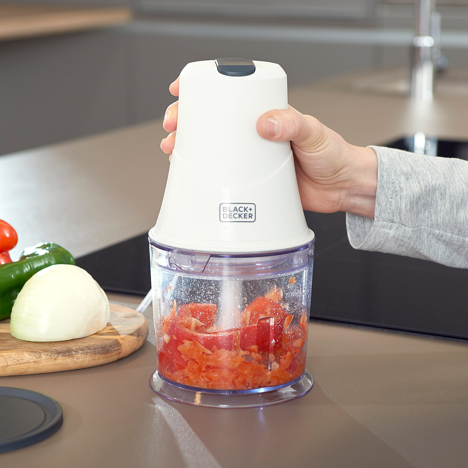 Una persona che taglia i pomodori in un tritatutto BLACK+DECKER.