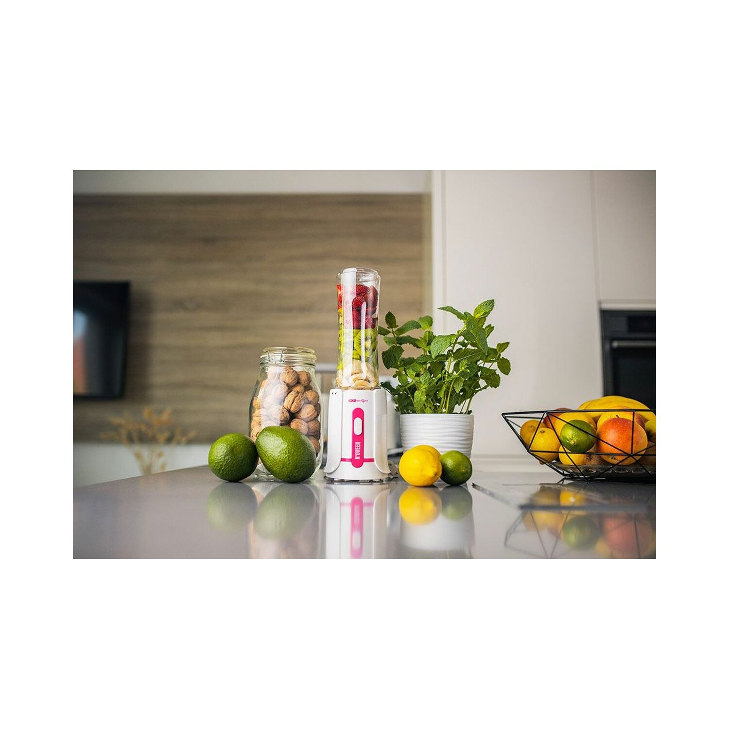 Blender z owocami i orzechami na szarym blacie.