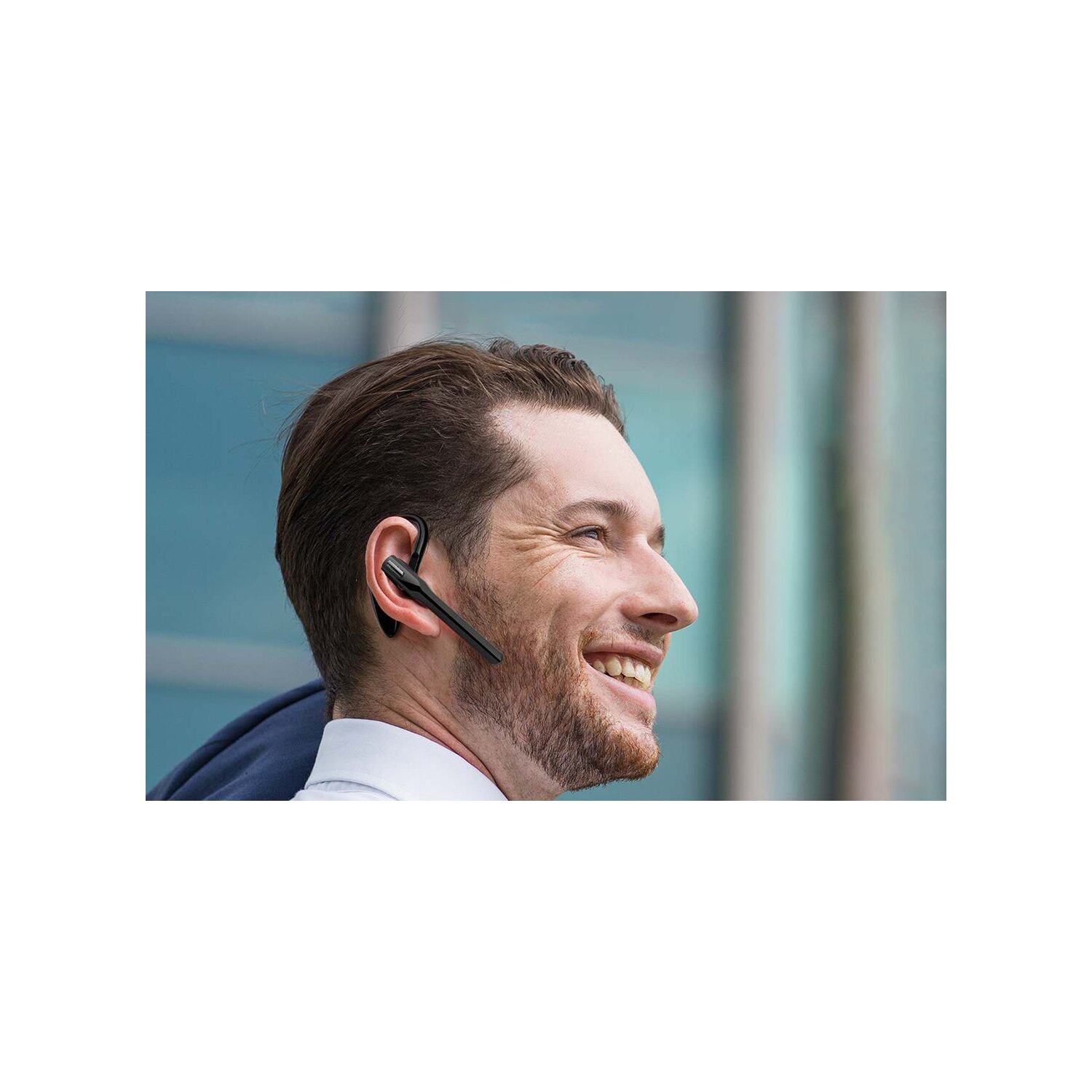 Mann mit schwarzem Headset, lächelnd, mit einem Bürogebäude im Hintergrund.