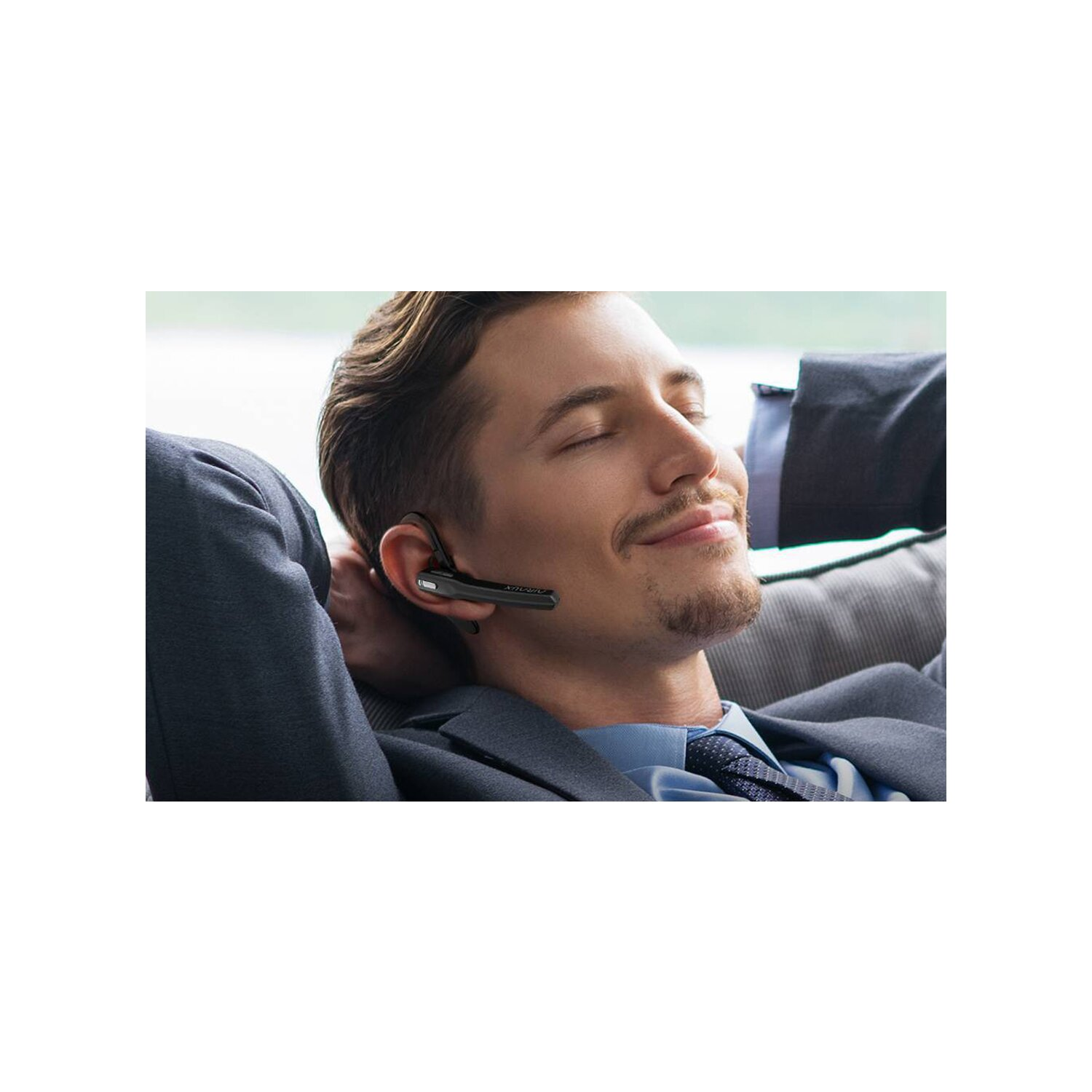 Mann mit Headset auf einem Sofa. Lächelnd und entspannt.