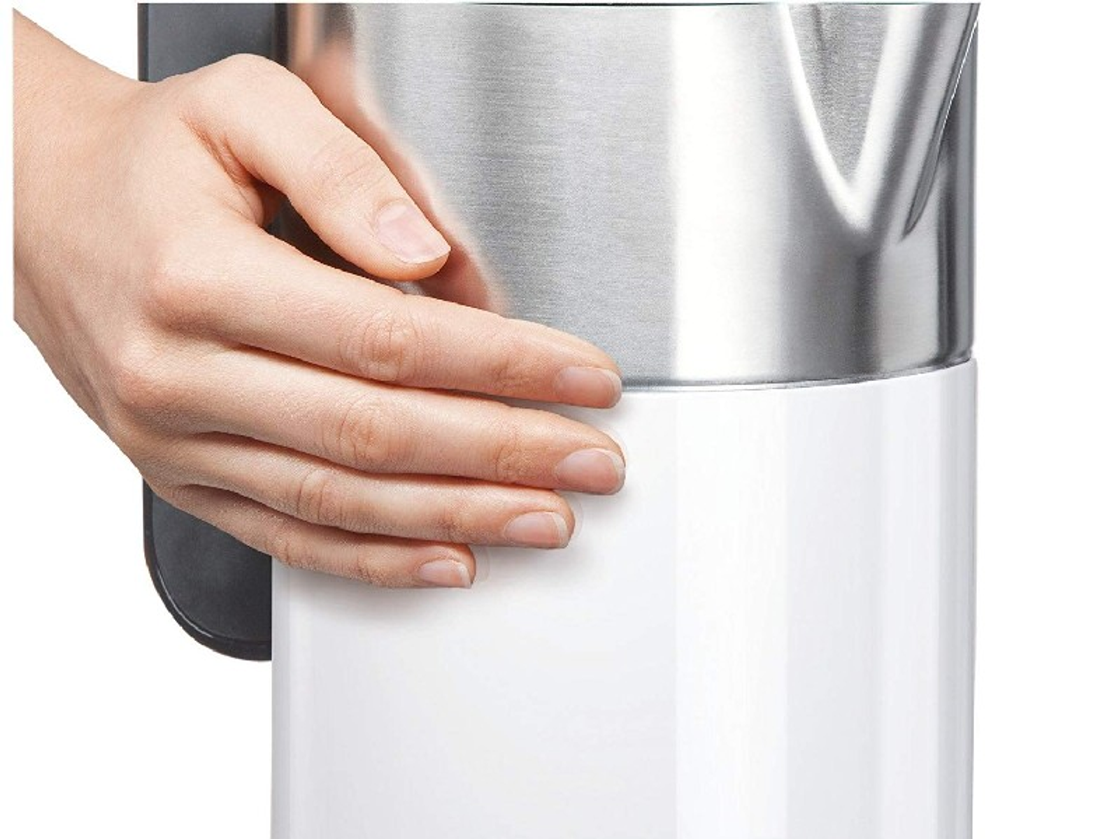 Dłoń trzyma biały i srebrny czajnik elektryczny.