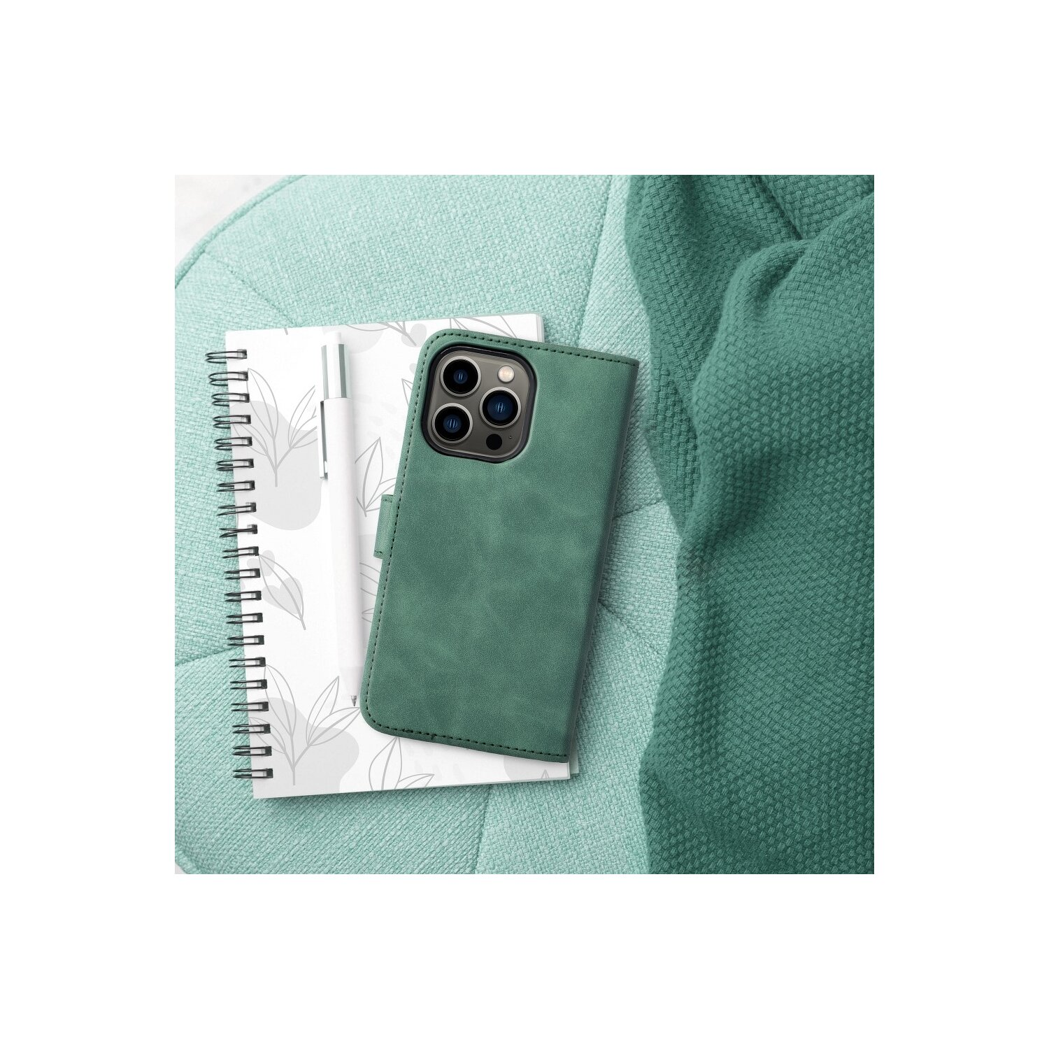 Custodia verde per telefono con quaderno e penna su superficie blu.