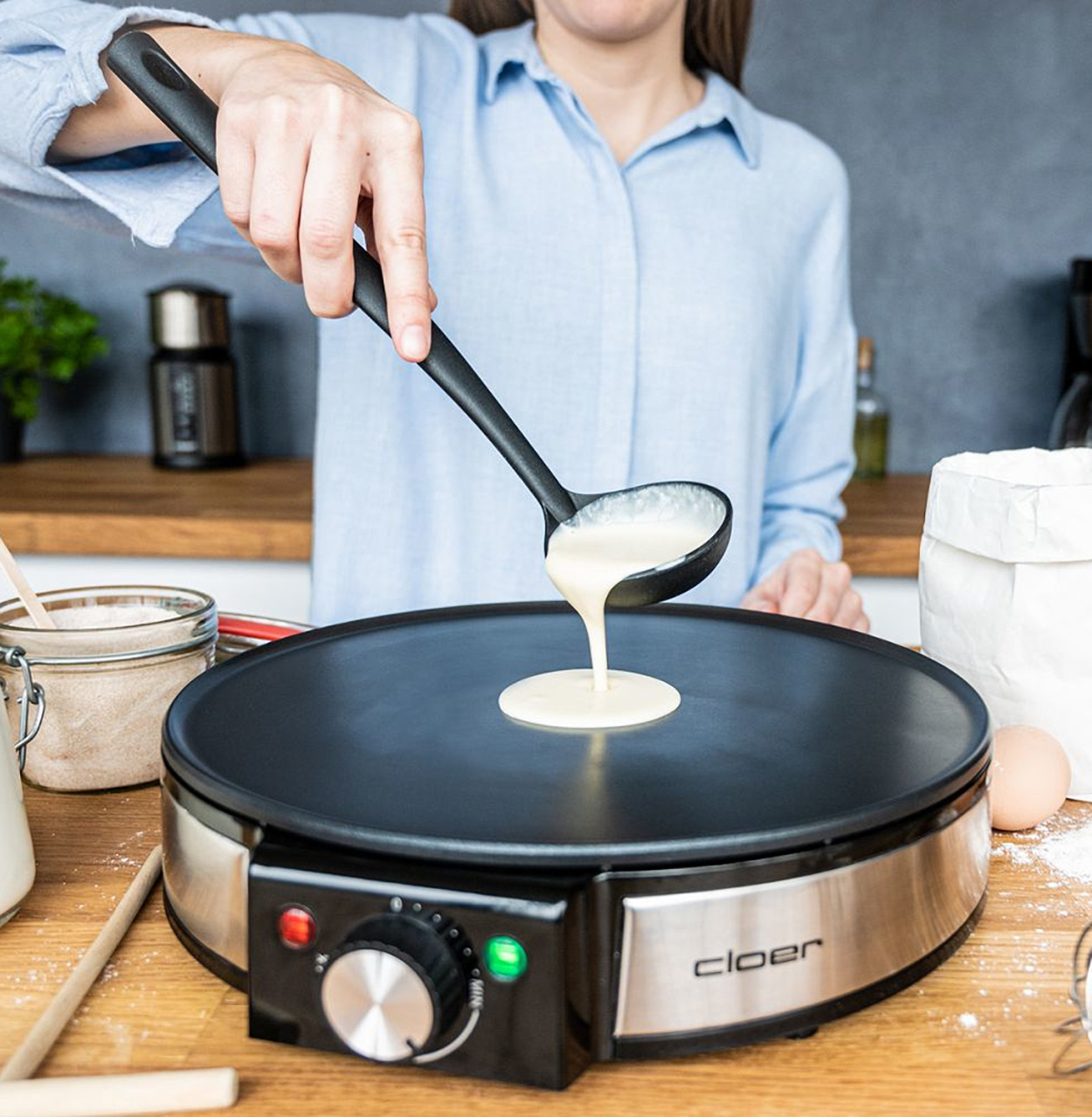Kobieta wlewa ciasto z chochli na patelnię do naleśników.